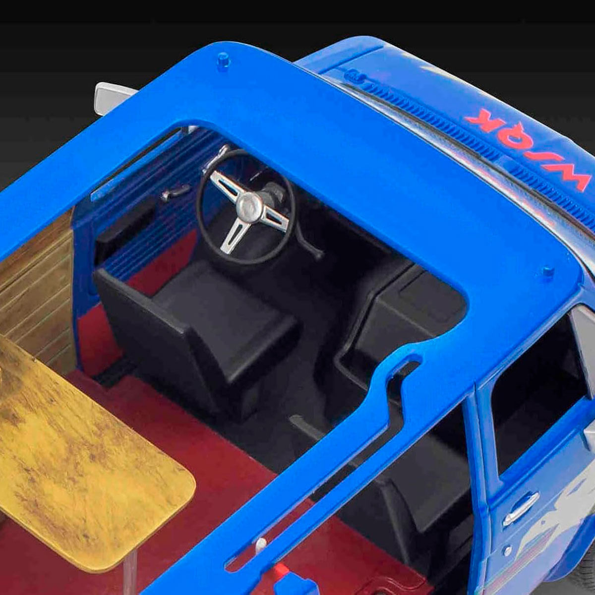 Vue intérieure d'une camionnette jouet bleue avec sièges, table et volant.