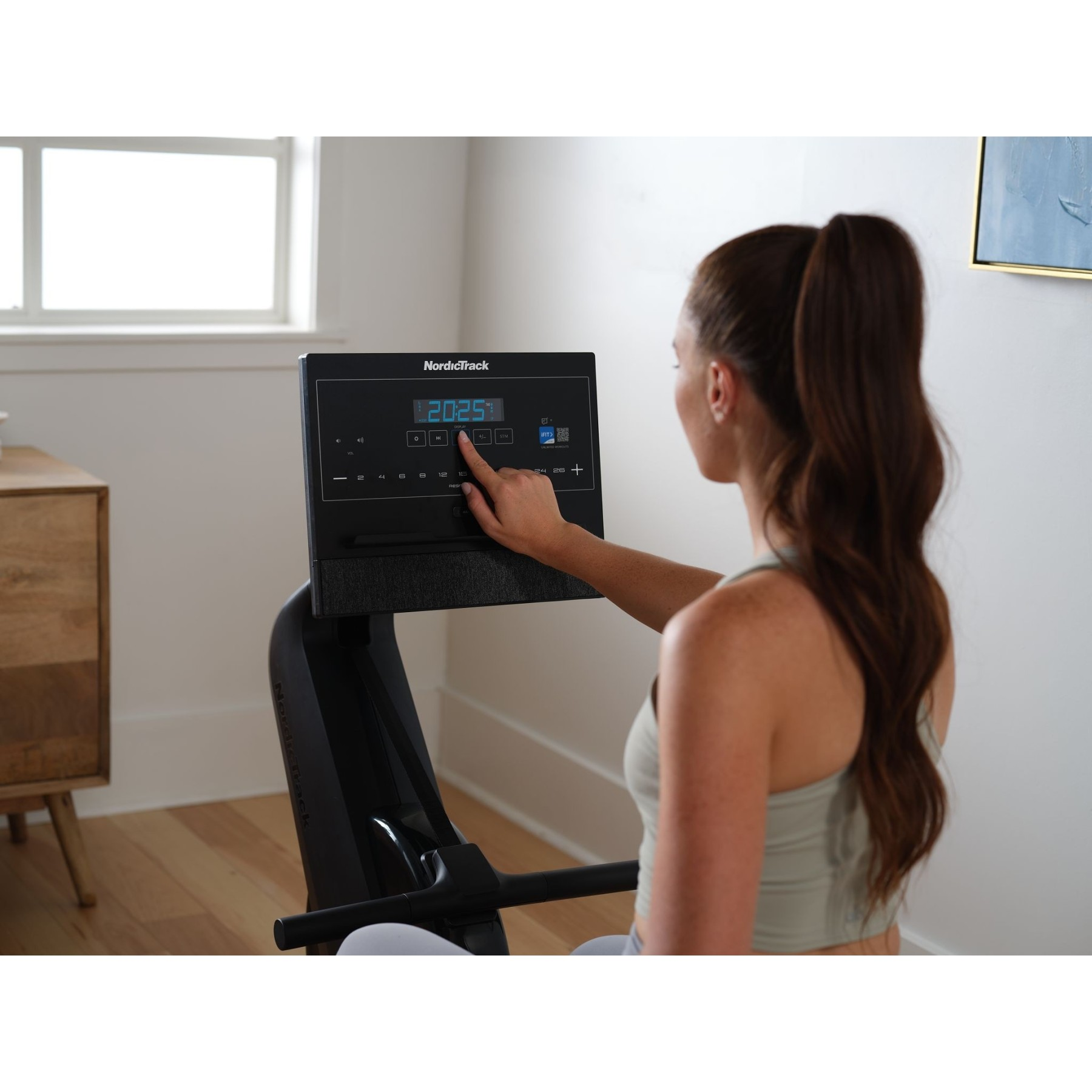 Eine Frau mit Pferdeschwanz benutzt ein NordicTrack-Rudergerät mit Display.