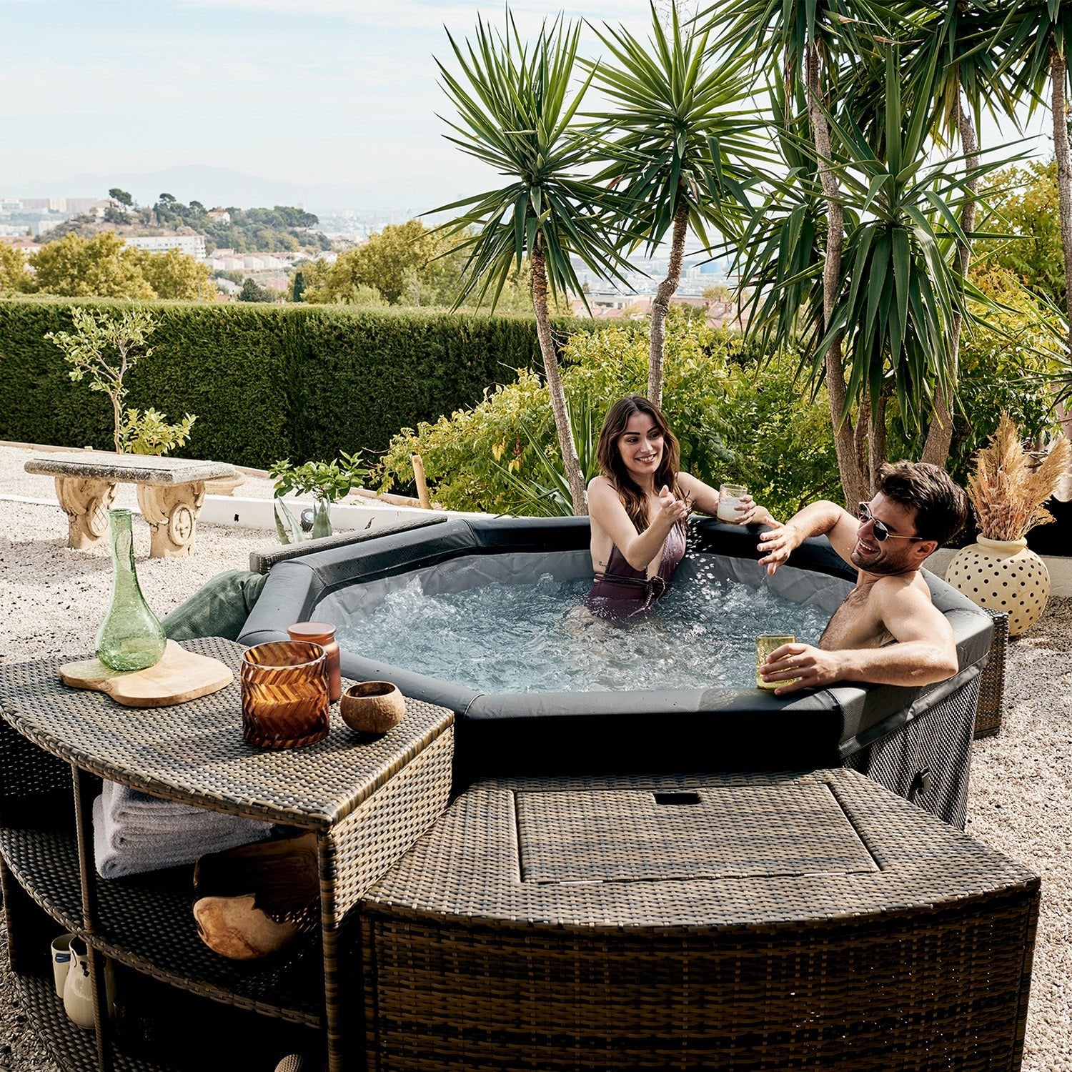 Una pareja relajándose en un jacuzzi exterior con palmeras al fondo.
