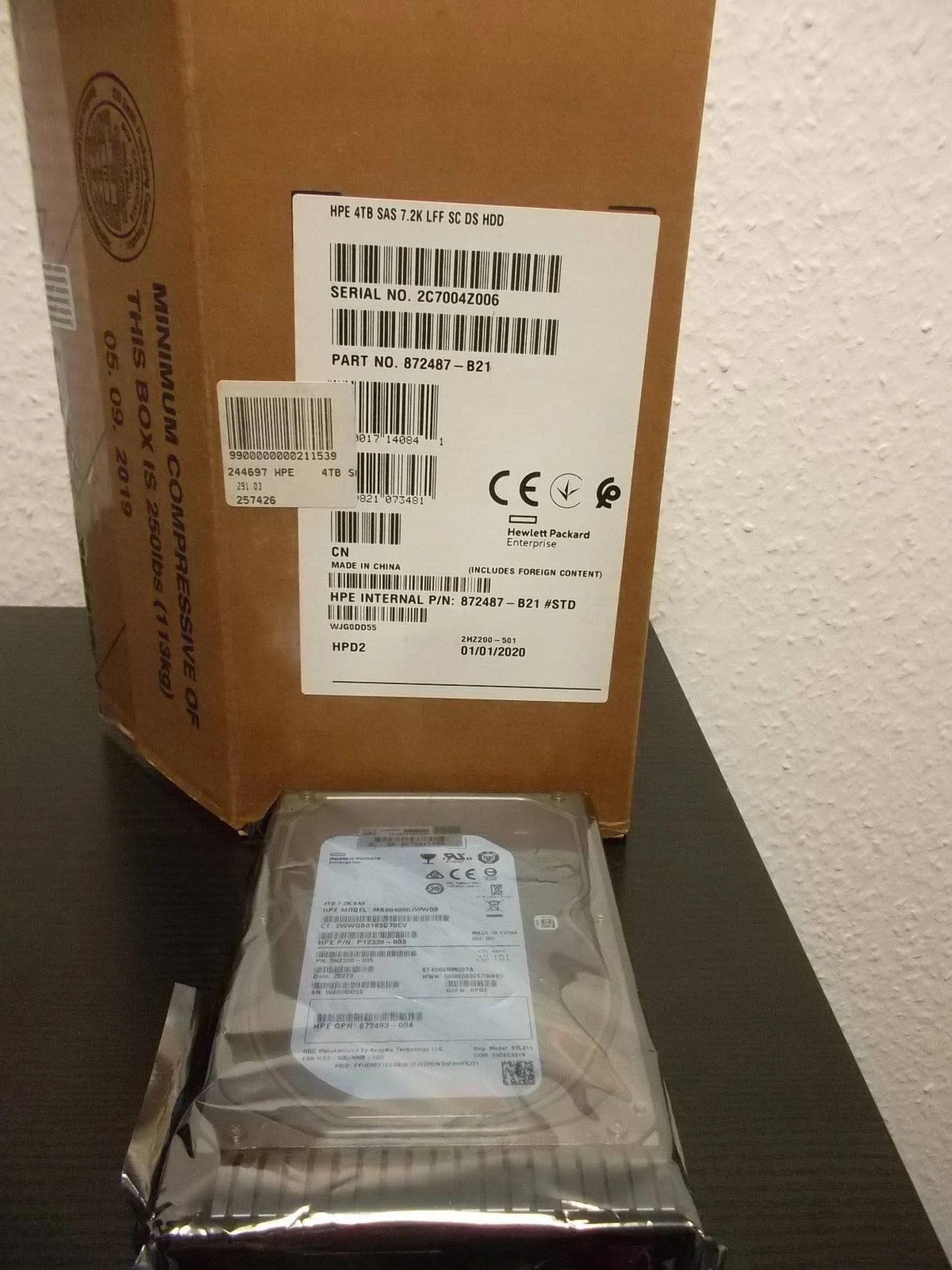 Dysk HPE 4TB SAS znajduje się przed pudełkiem z etykietami.