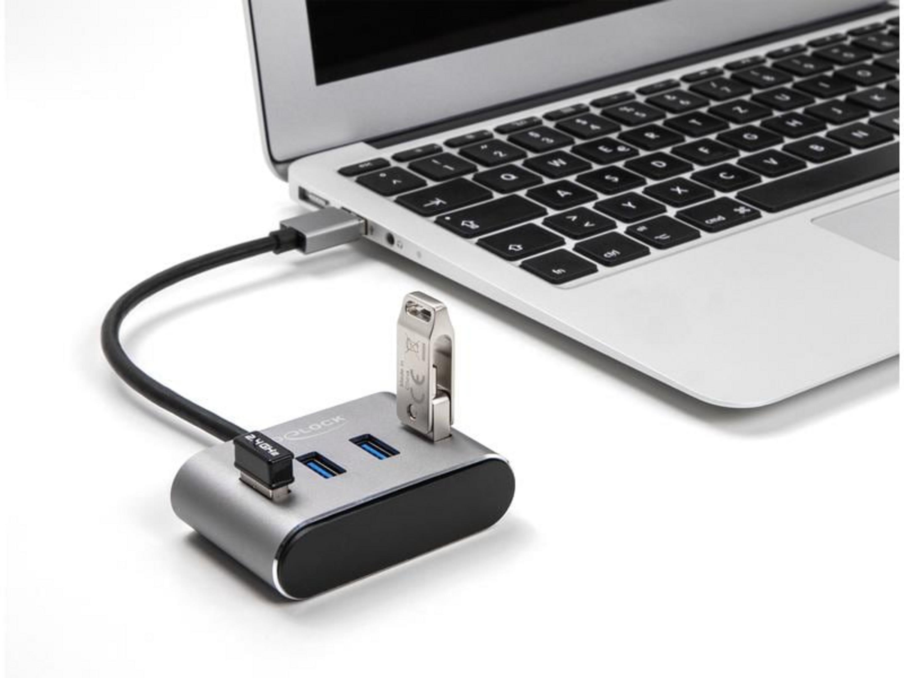 Un hub USB argentato a due porte è collegato a un laptop, con un'unità USB inserita.
