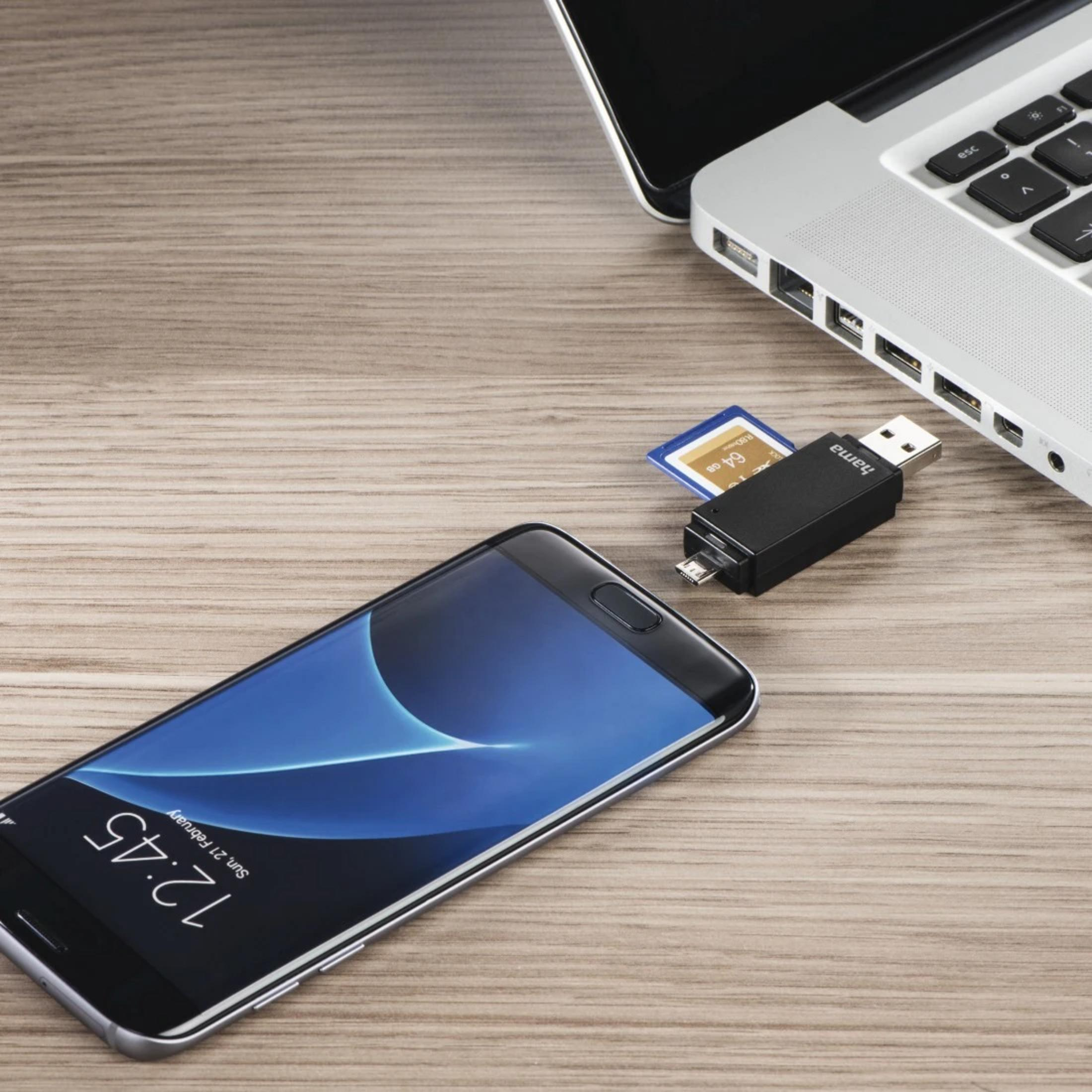 Smartfon, karta SD i adapter USB na drewnianym stole obok laptopa.