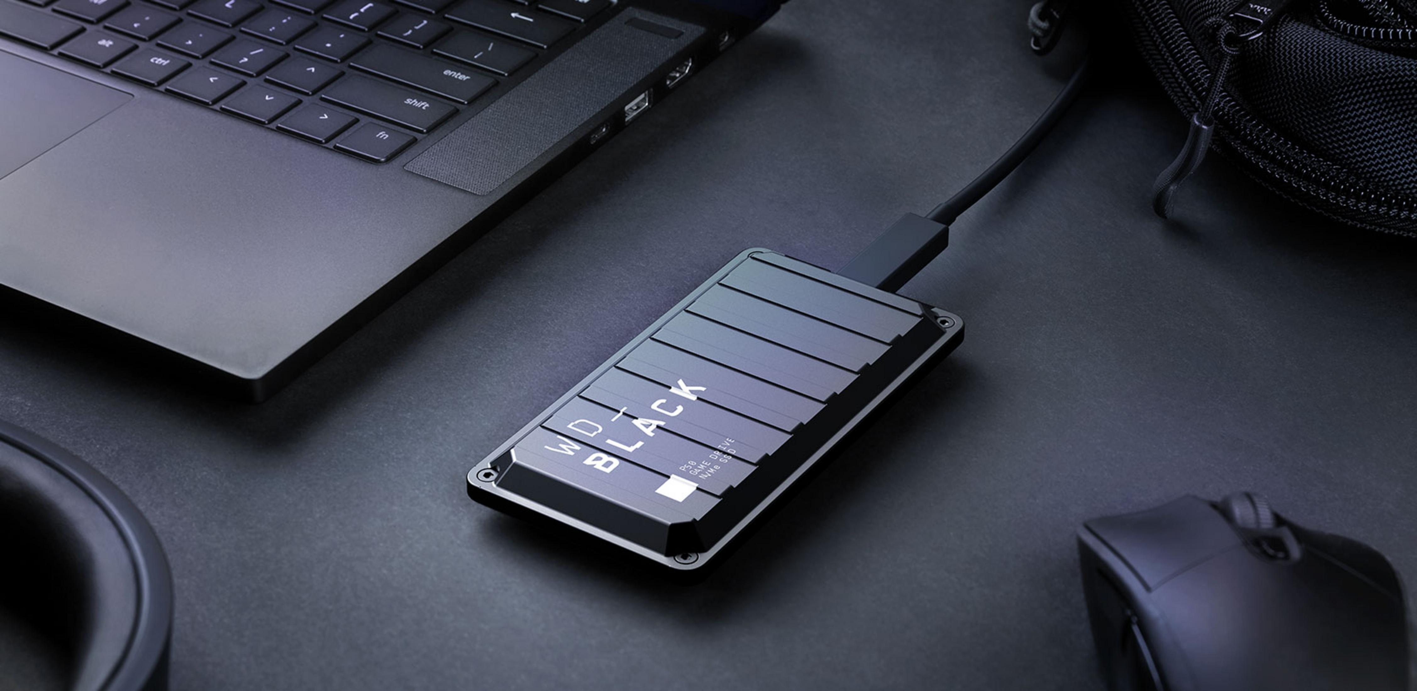 Eine schwarze WD_BLACK P50 NVMe SSD ist an einen Laptop neben einer Maus angeschlossen.