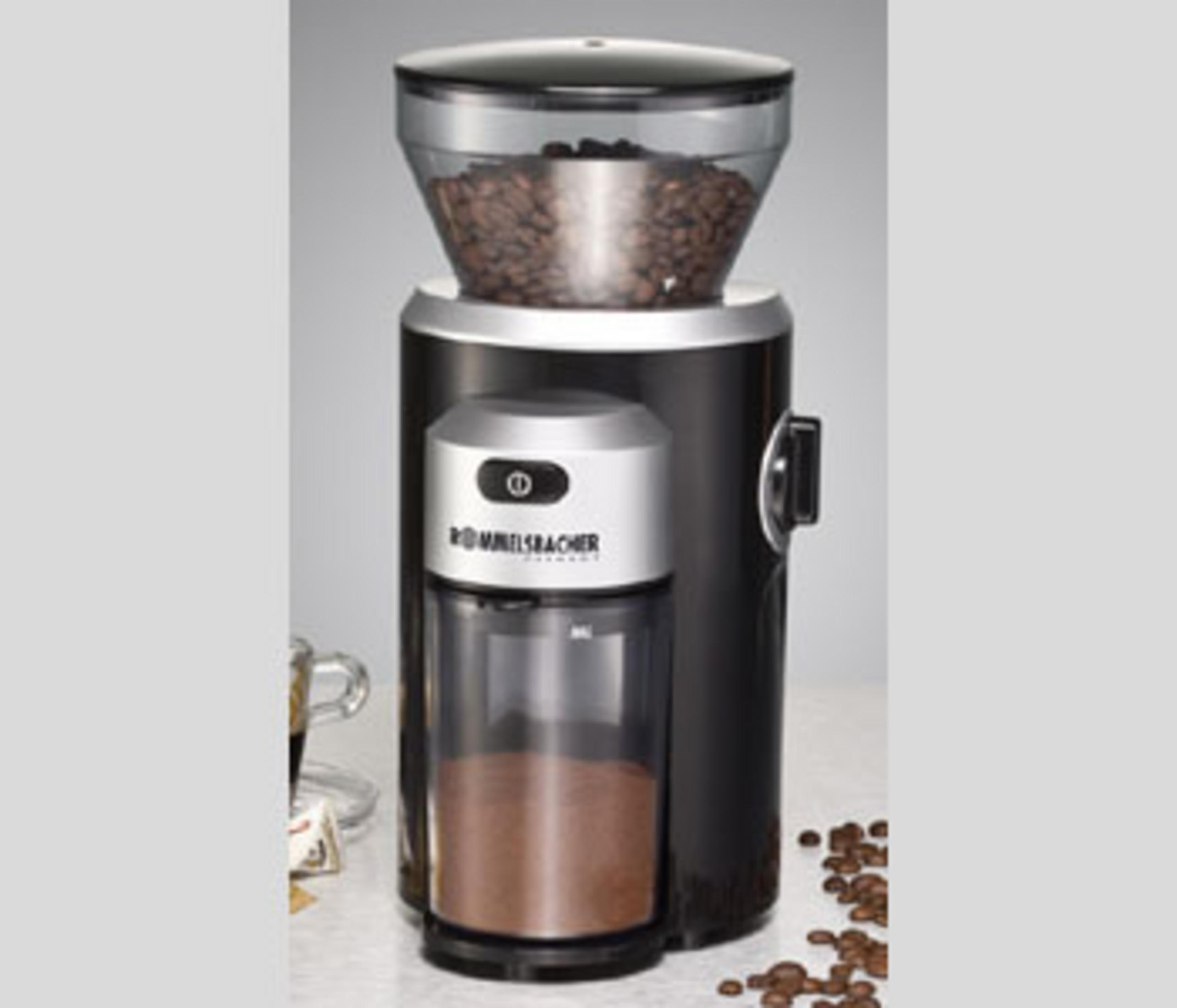 Kaffeemühle mit Bohnen oben und gemahlenem Kaffee unten. Daneben eine Tasse.