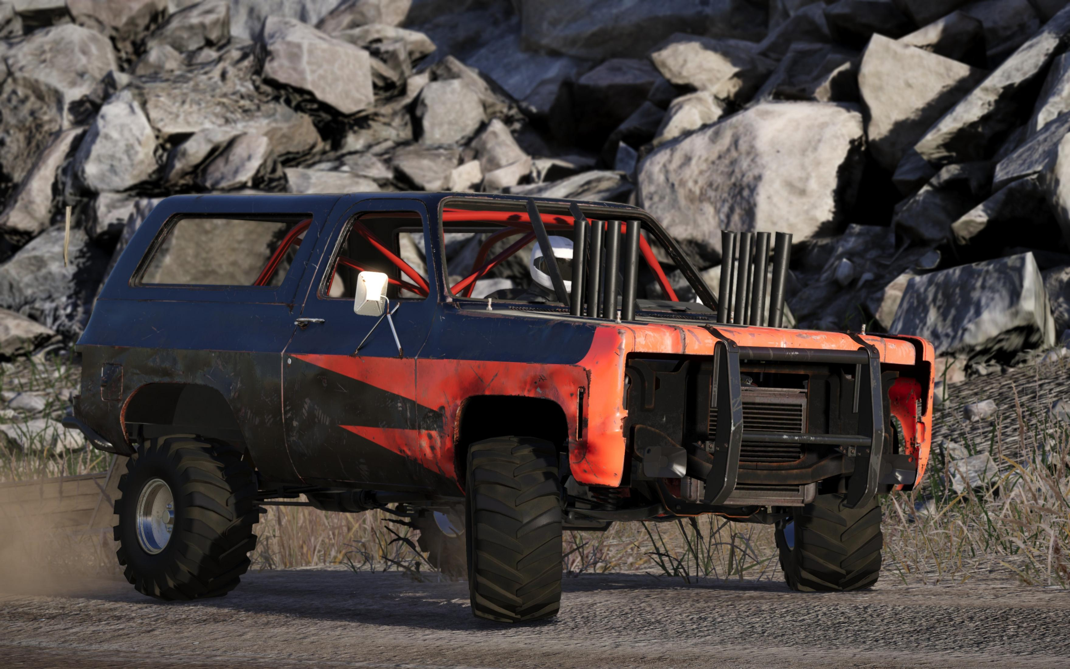 Een aangepaste offroad truck met rolkooi en uitlaatpijpen op rotsachtig terrein.