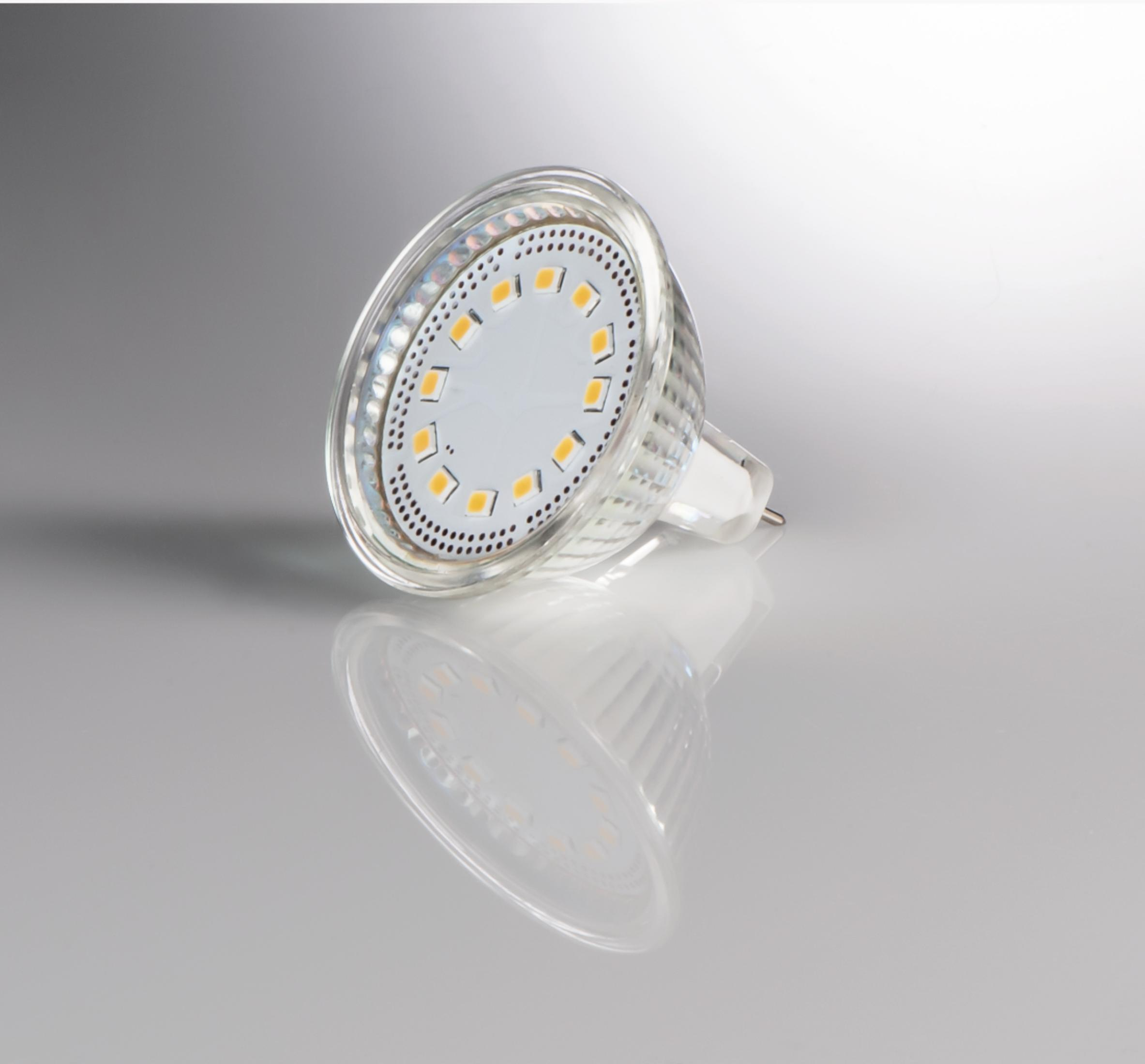 Una lampadina LED trasparente con luci gialle e base argentata su sfondo grigio.