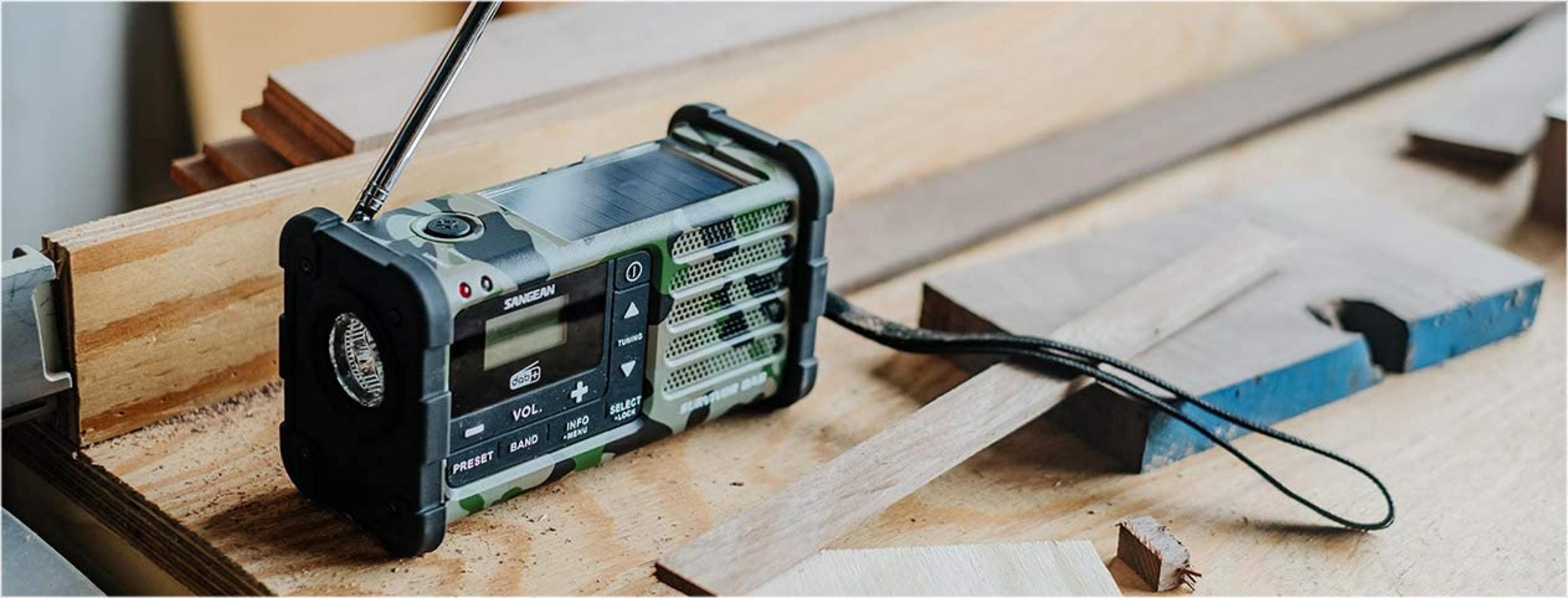 Una radio mimetica con pannello solare poggia su banchi di legno.