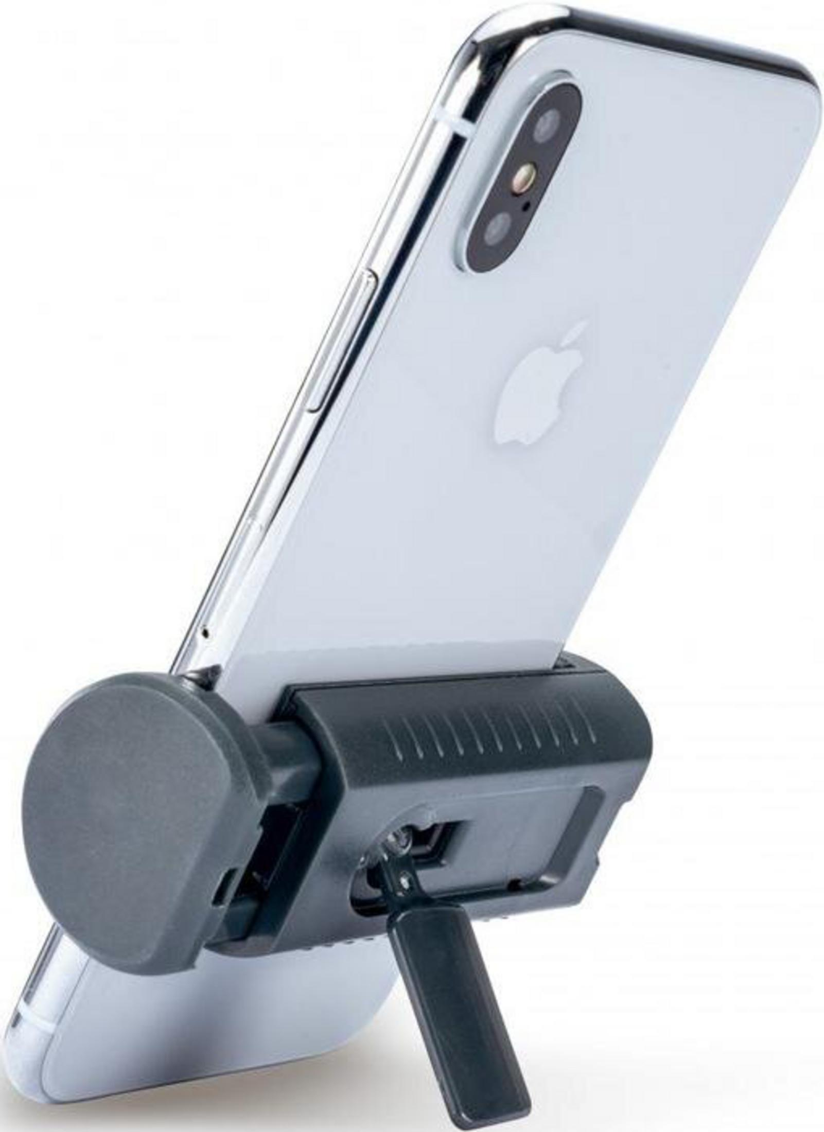 Un smartphone plateado sobre un soporte oscuro, sobre fondo blanco.