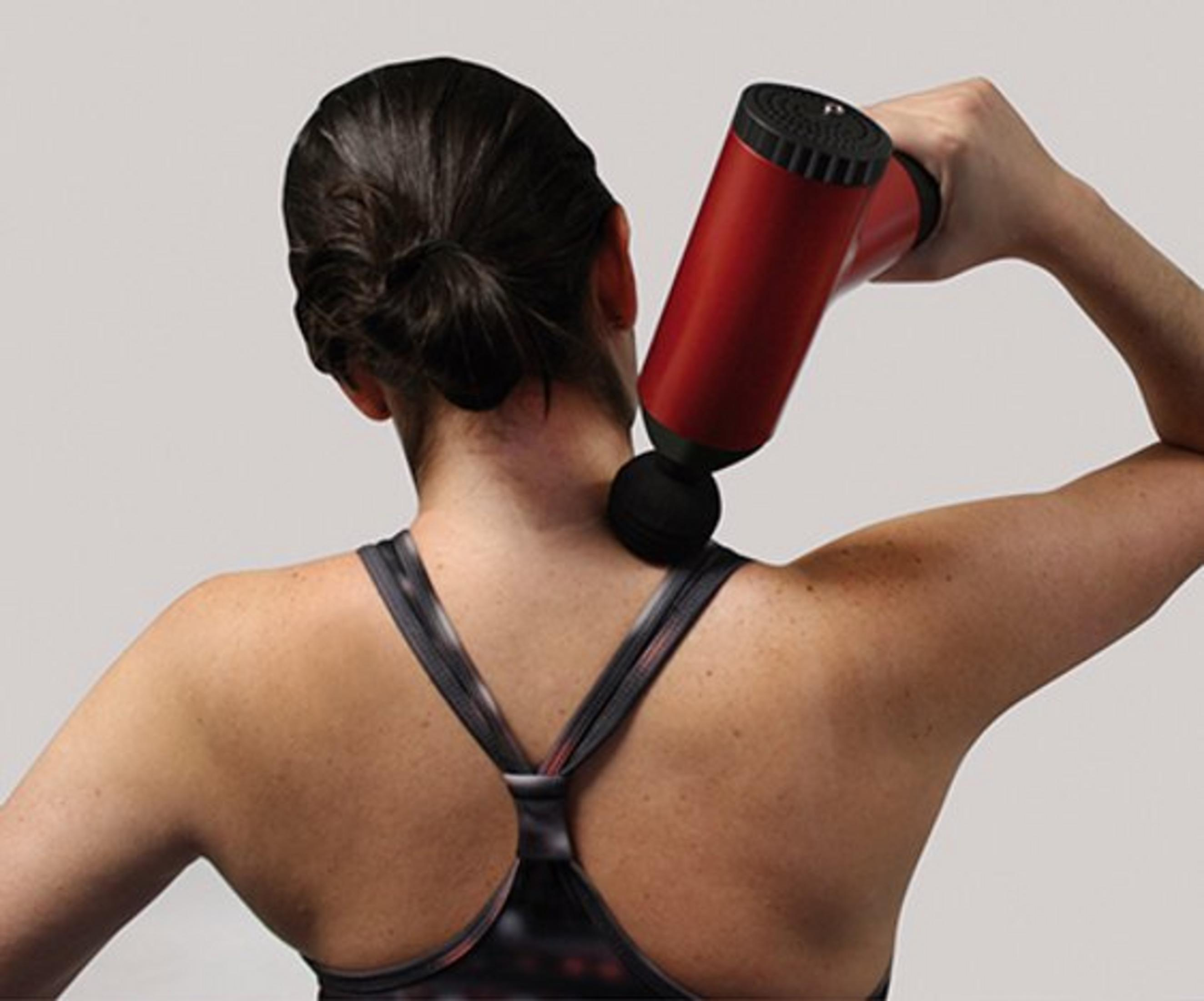 Pistolet de massage rouge sur le cou et l'épaule d'une femme.