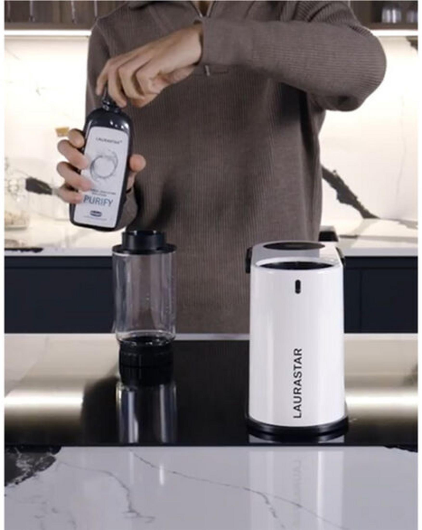 Person öffnet Flasche über Wasserbehälter neben weißem Gerät.