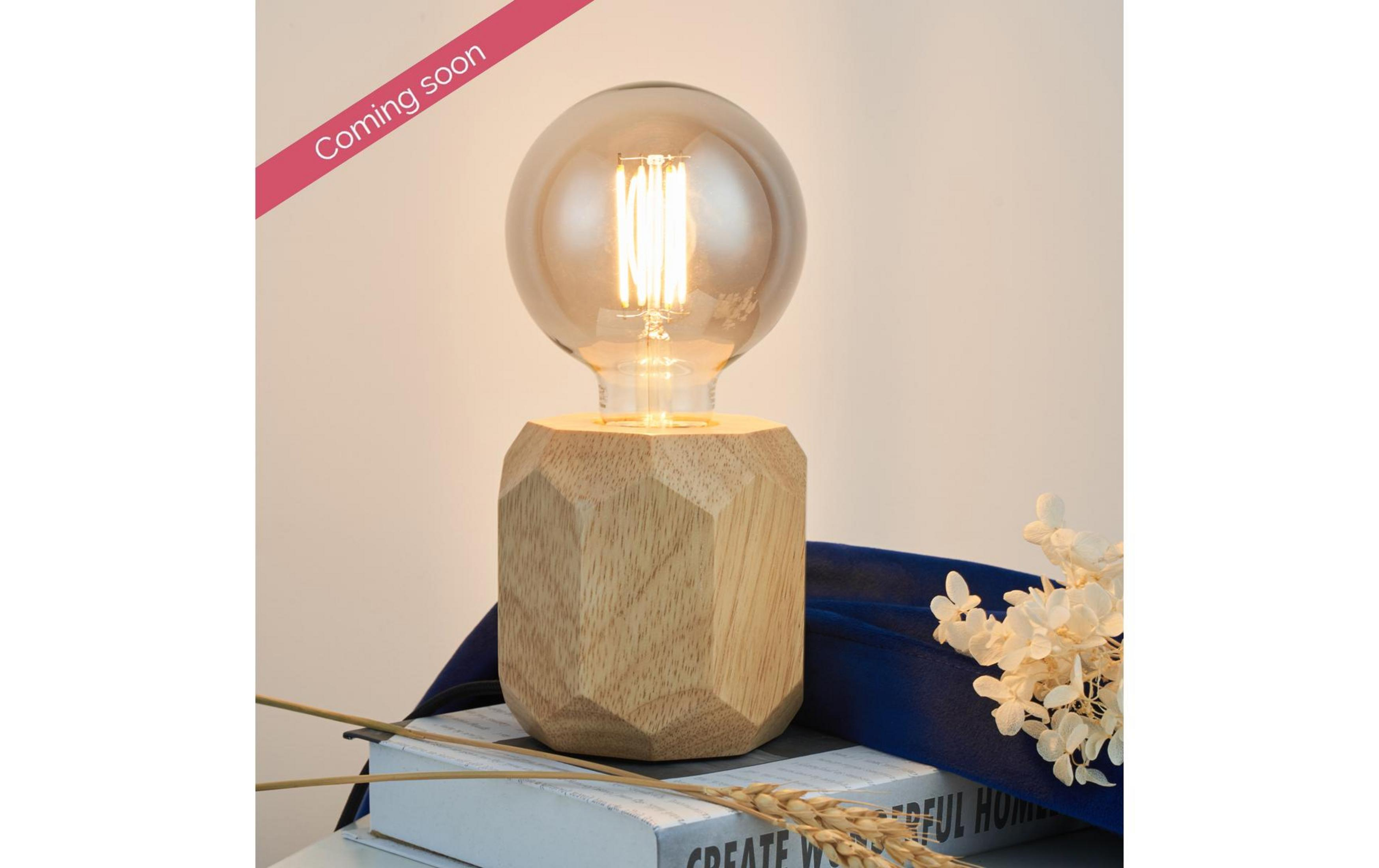 Eine Lampe mit Holzsockel, Glühbirne und Trockenblumen.