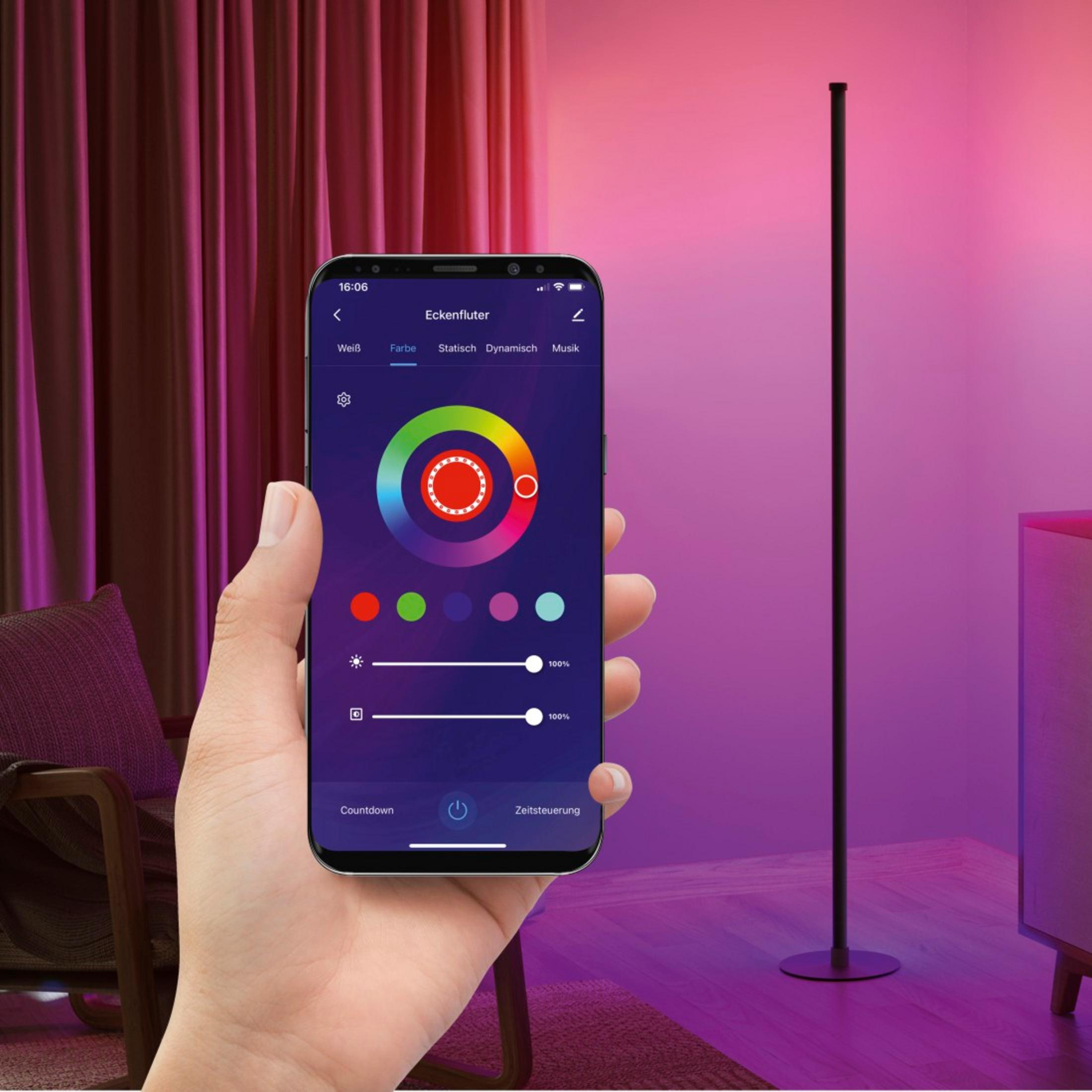 Mano tiene smartphone con app che controlla lampada da terra in stanza viola.