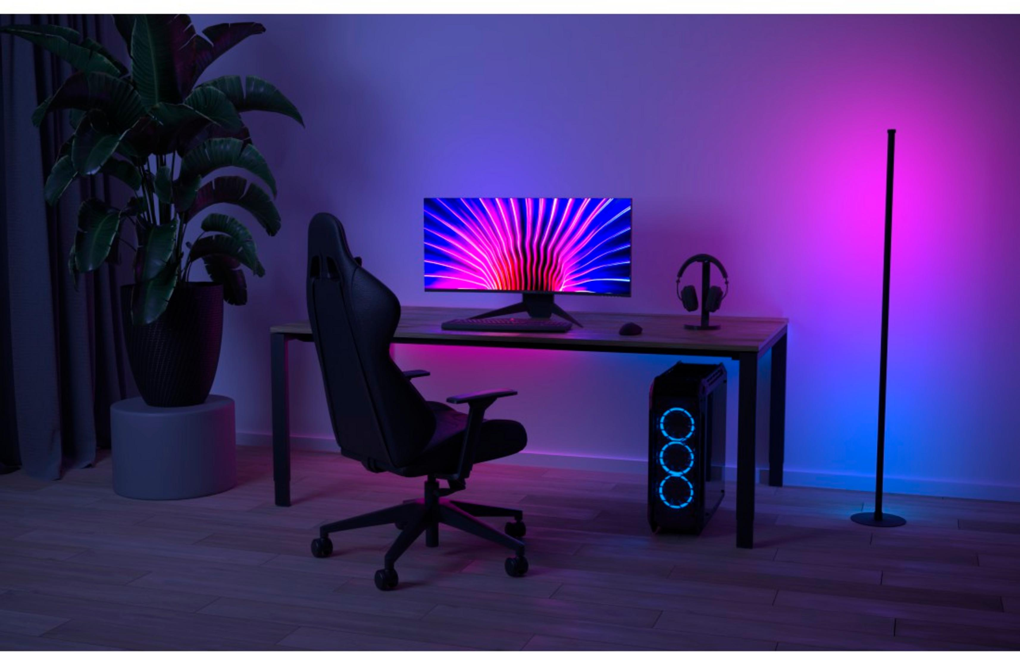 Una postazione da gaming con sedia, scrivania, computer e monitor illuminato.