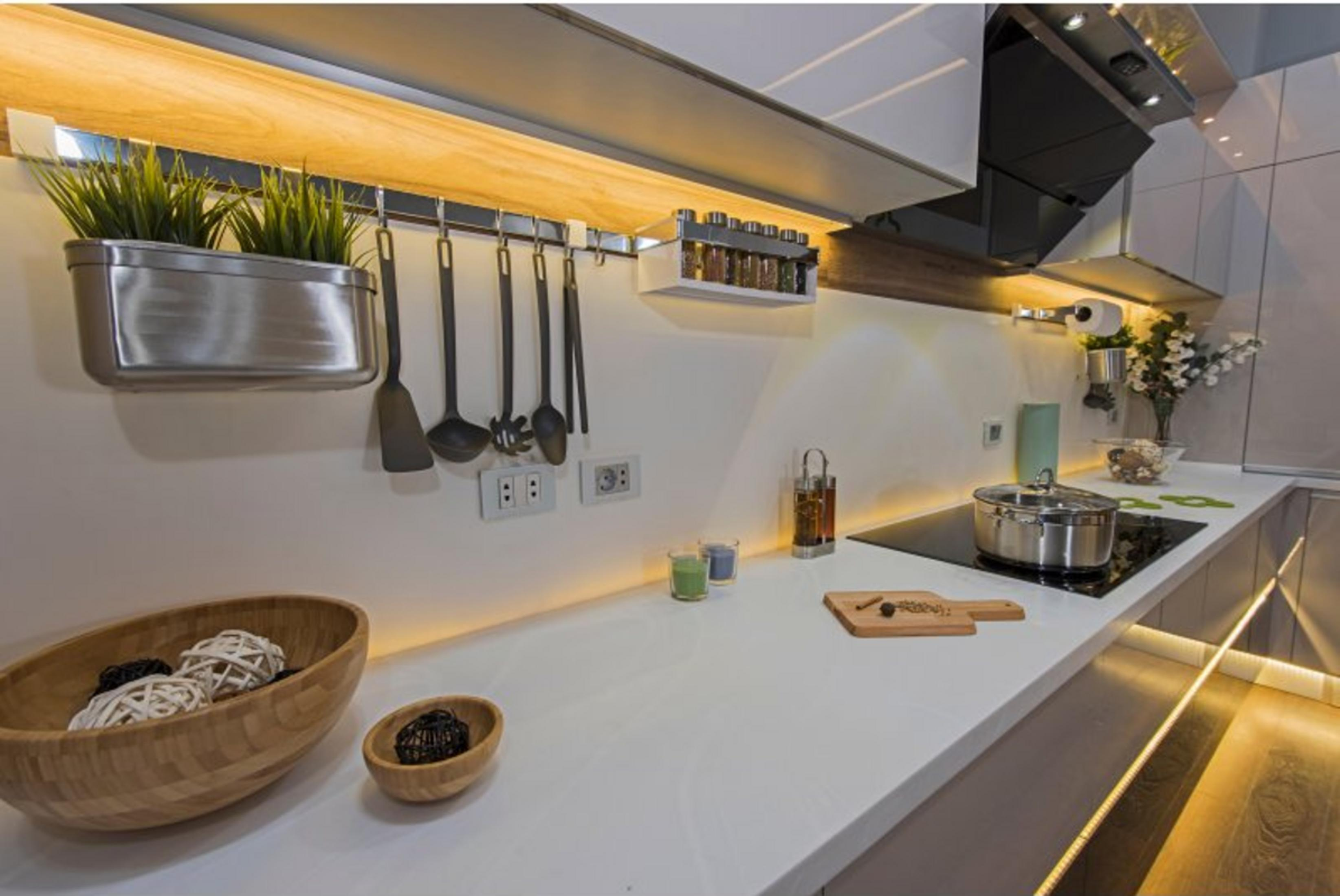 Moderne Küche mit Metalltopf auf Induktionskochfeld, Holzlöffeln und Pflanzen.