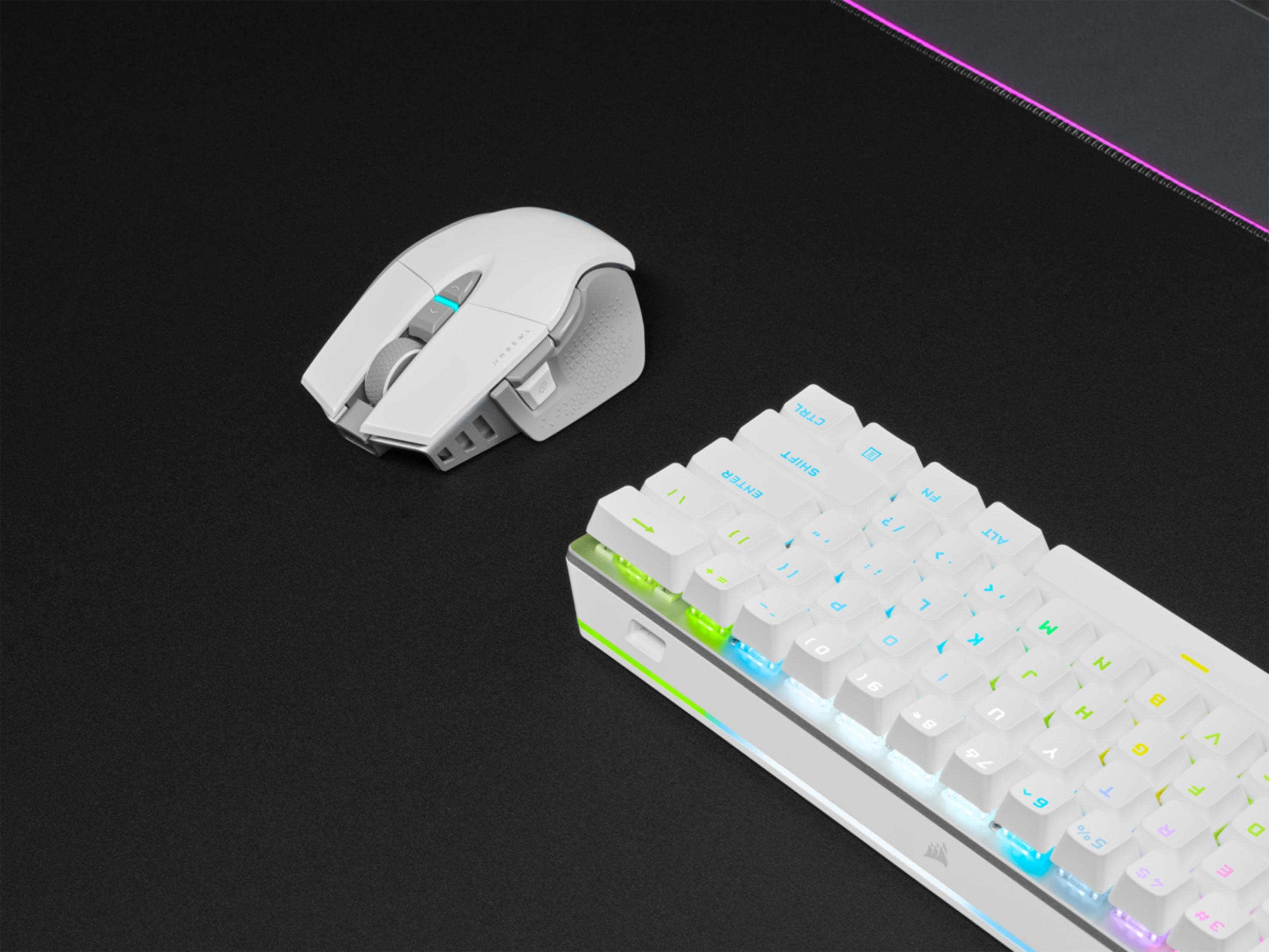 Un teclado y ratón blancos descansan sobre una alfombrilla negra con iluminación RGB.
