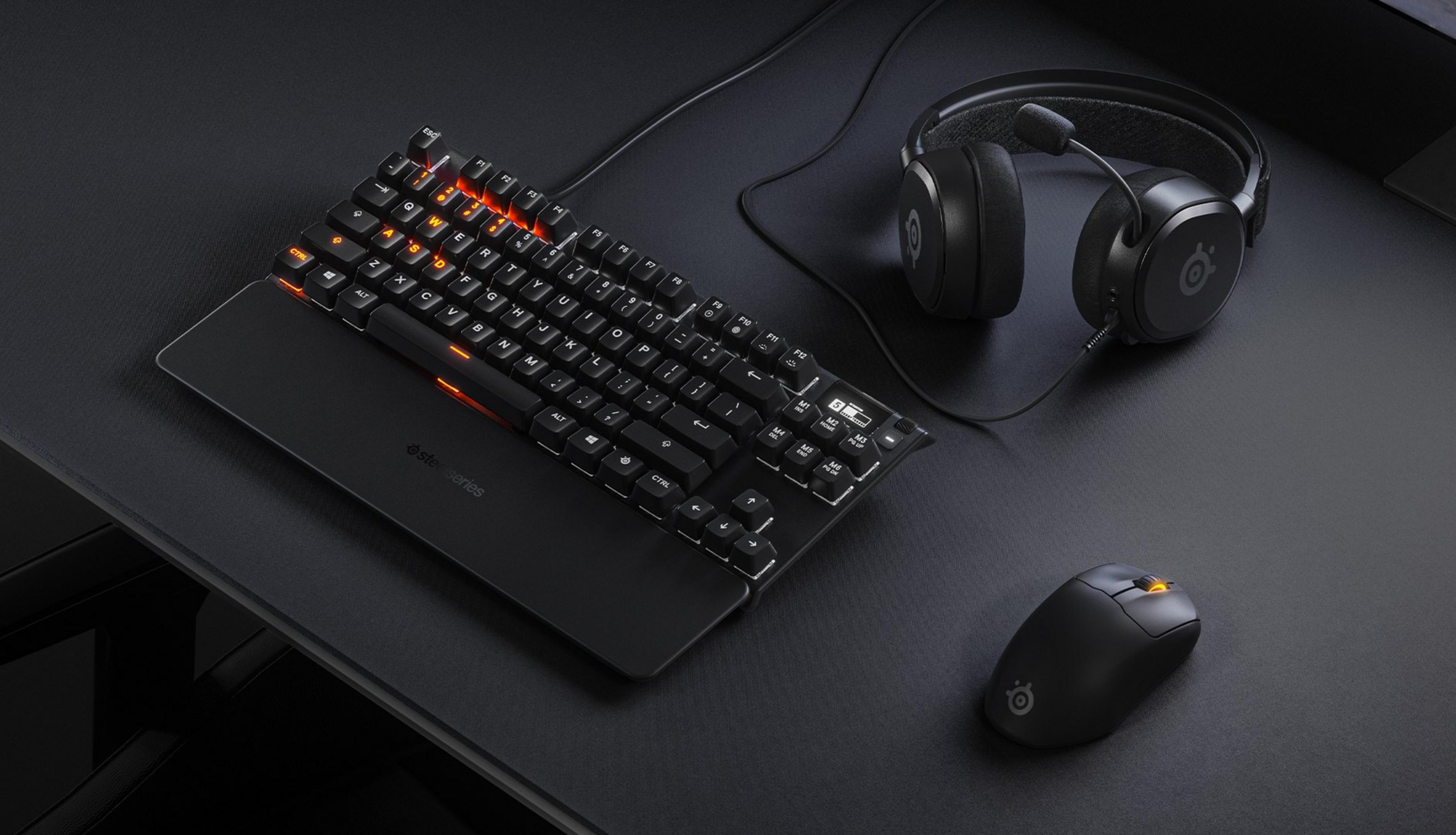 Schwarze Gaming-Tastatur, Maus und Kopfhörer mit orangefarbener Beleuchtung auf einer Matte.