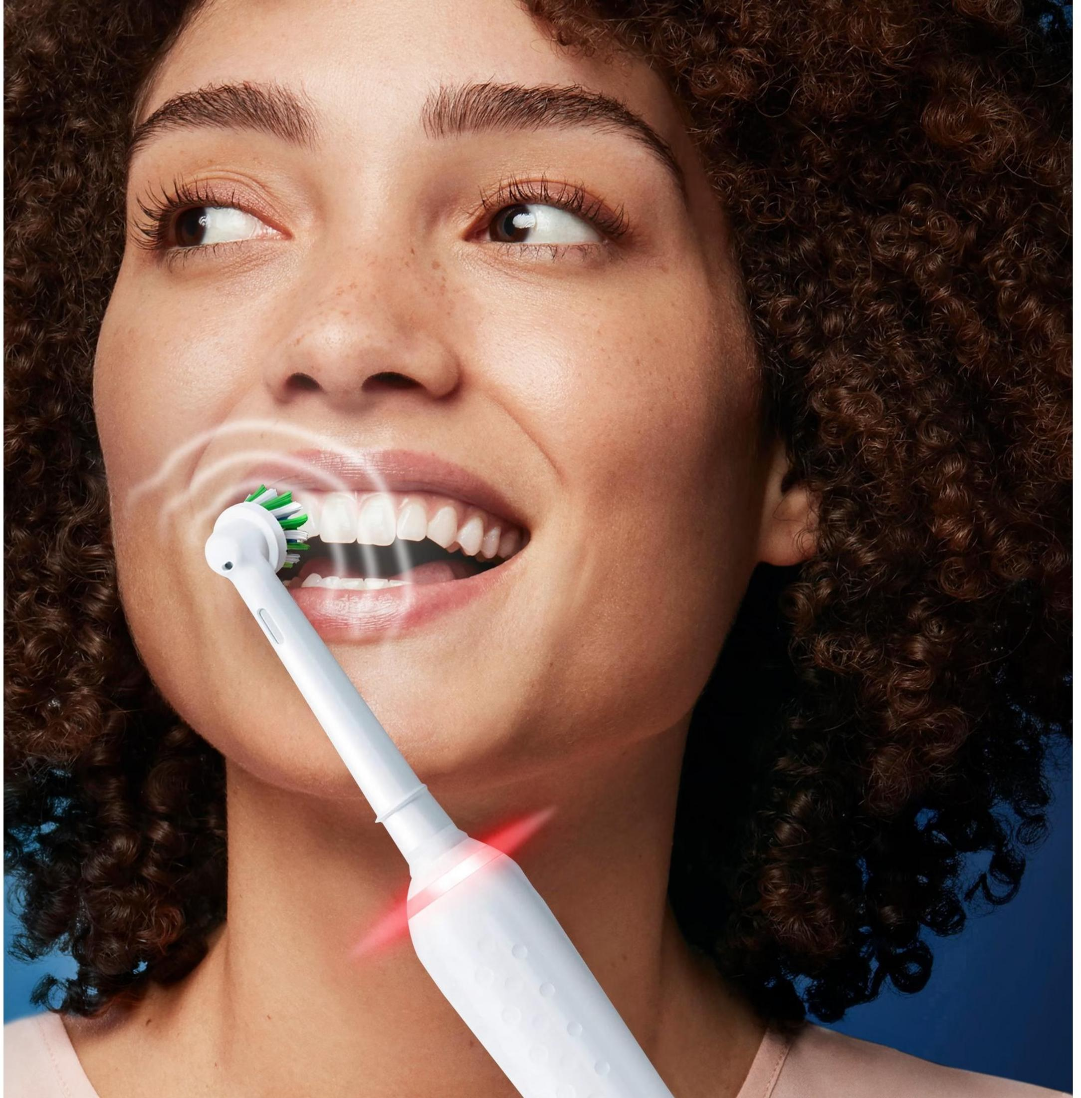 A woman brushing her teeth with an electric toothbrush.