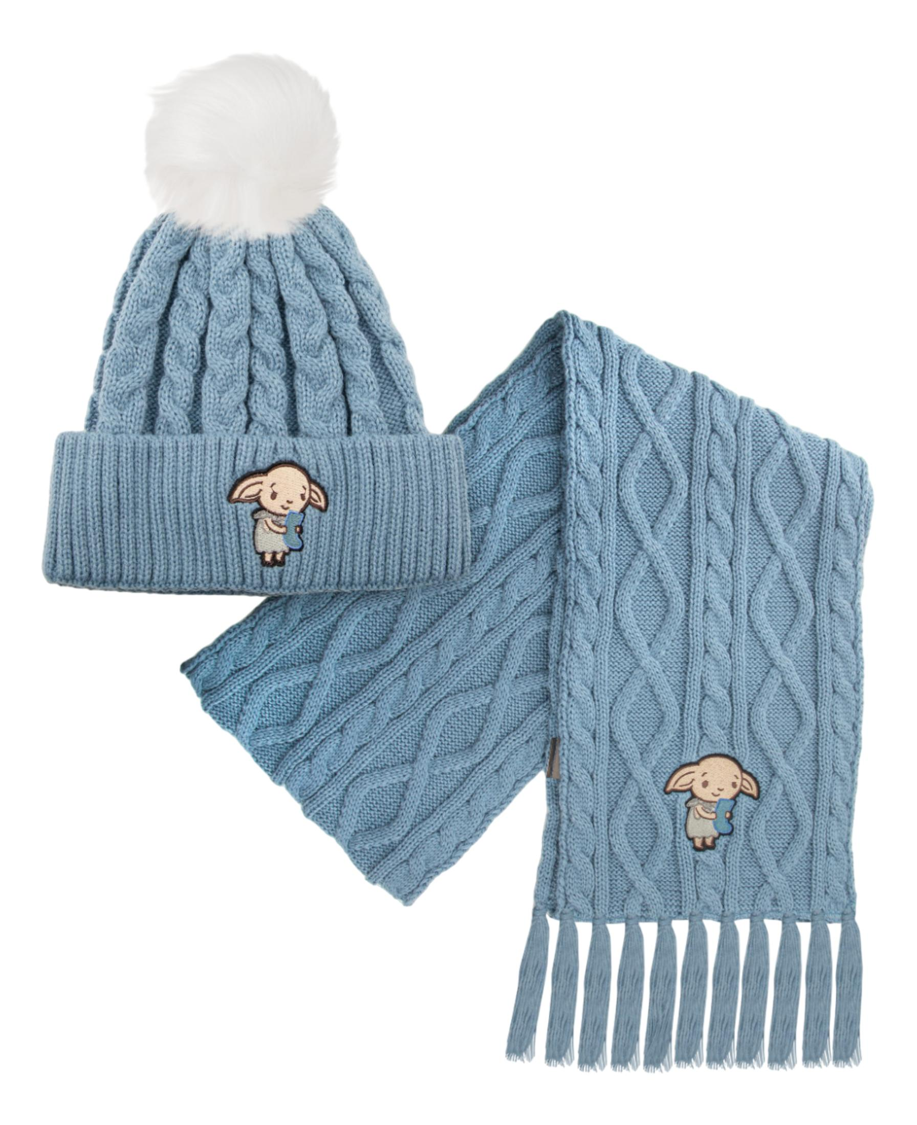 Hellblaue Strickmütze mit weißem Bommel und Schal mit Stickerei eines kleinen Wesens.