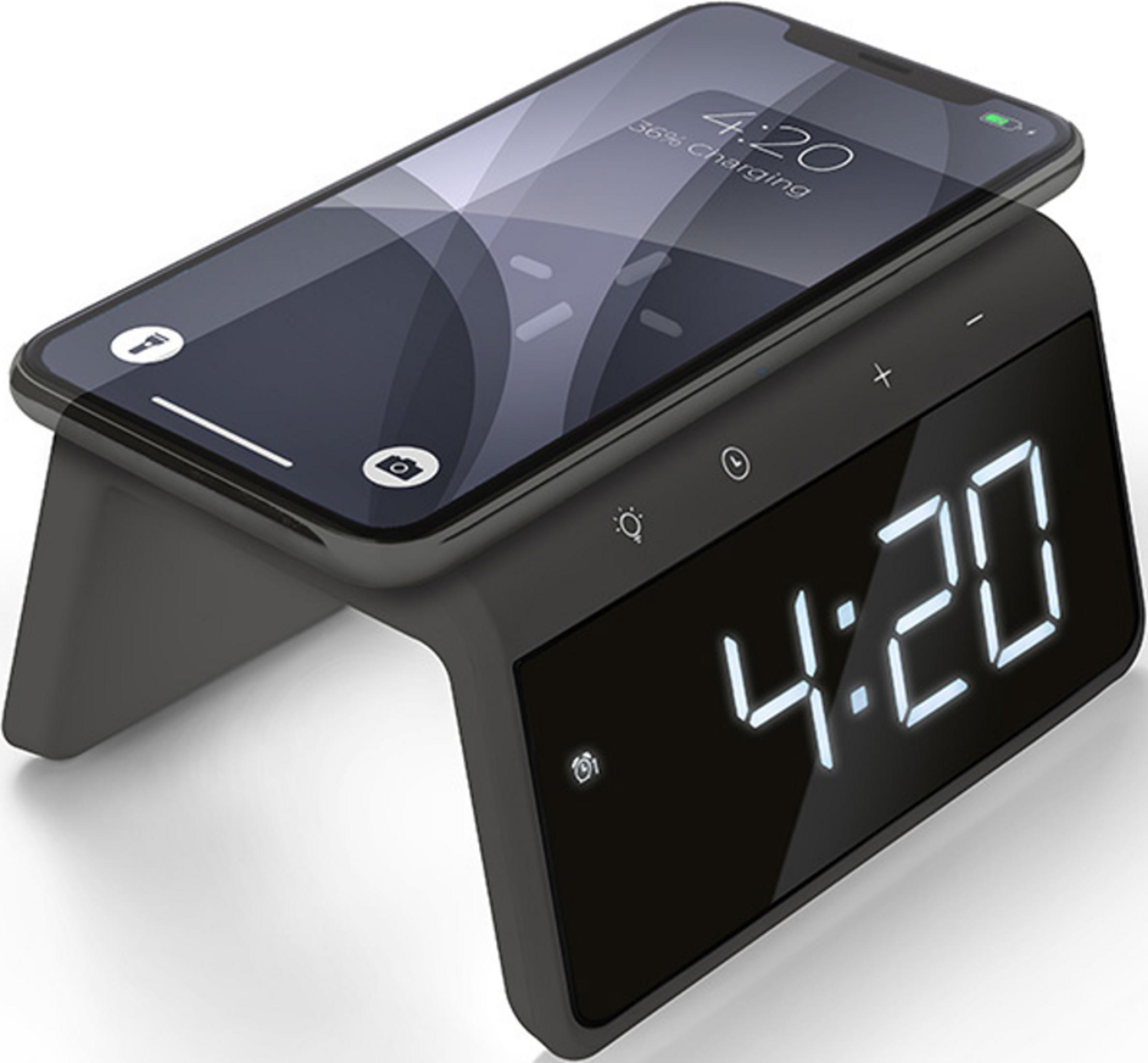 A smartphone charging on a black digital alarm clock.