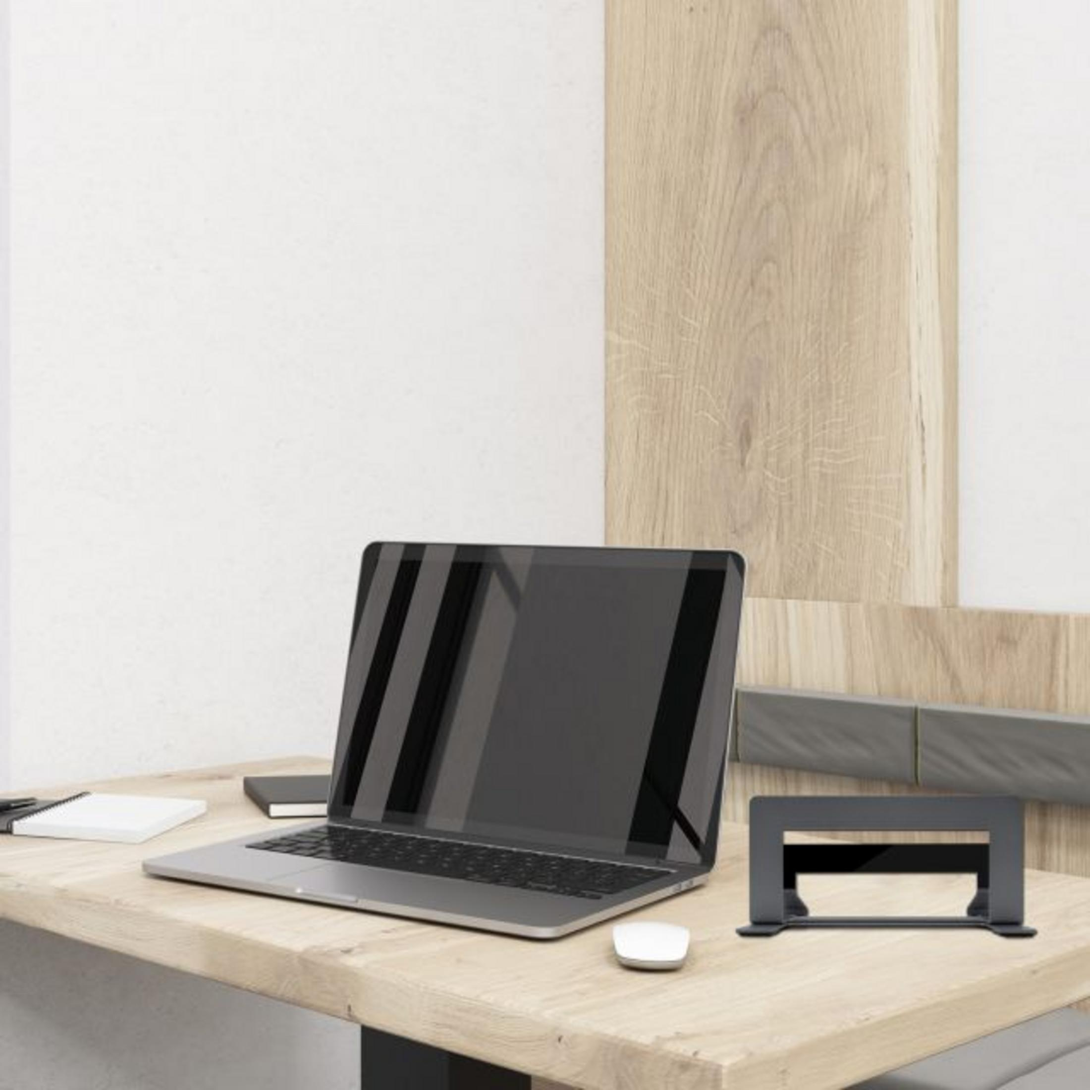 Ein moderner Schreibtisch mit Laptop, Maus, Notizblock und Ständer.