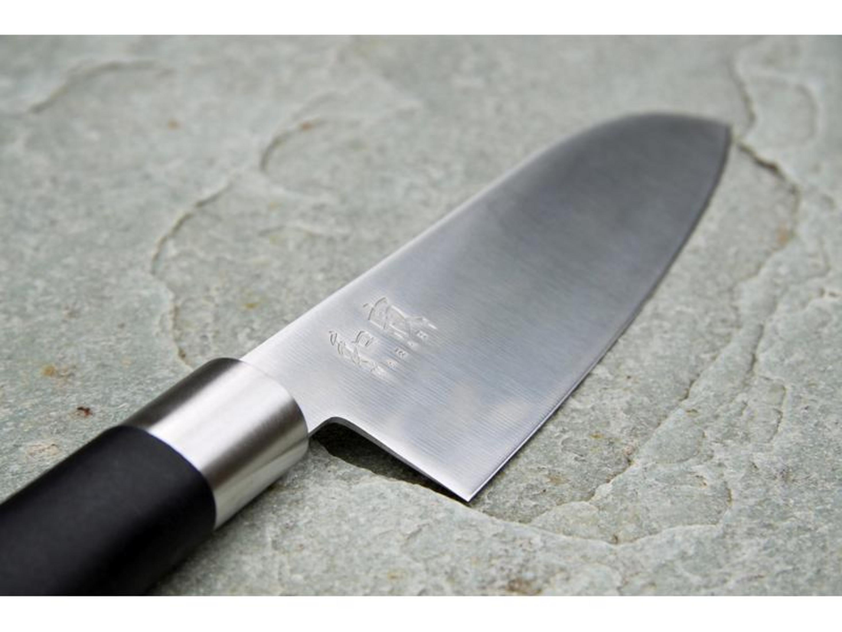 Un coltello da cucina con manico nero poggia sulla pietra.