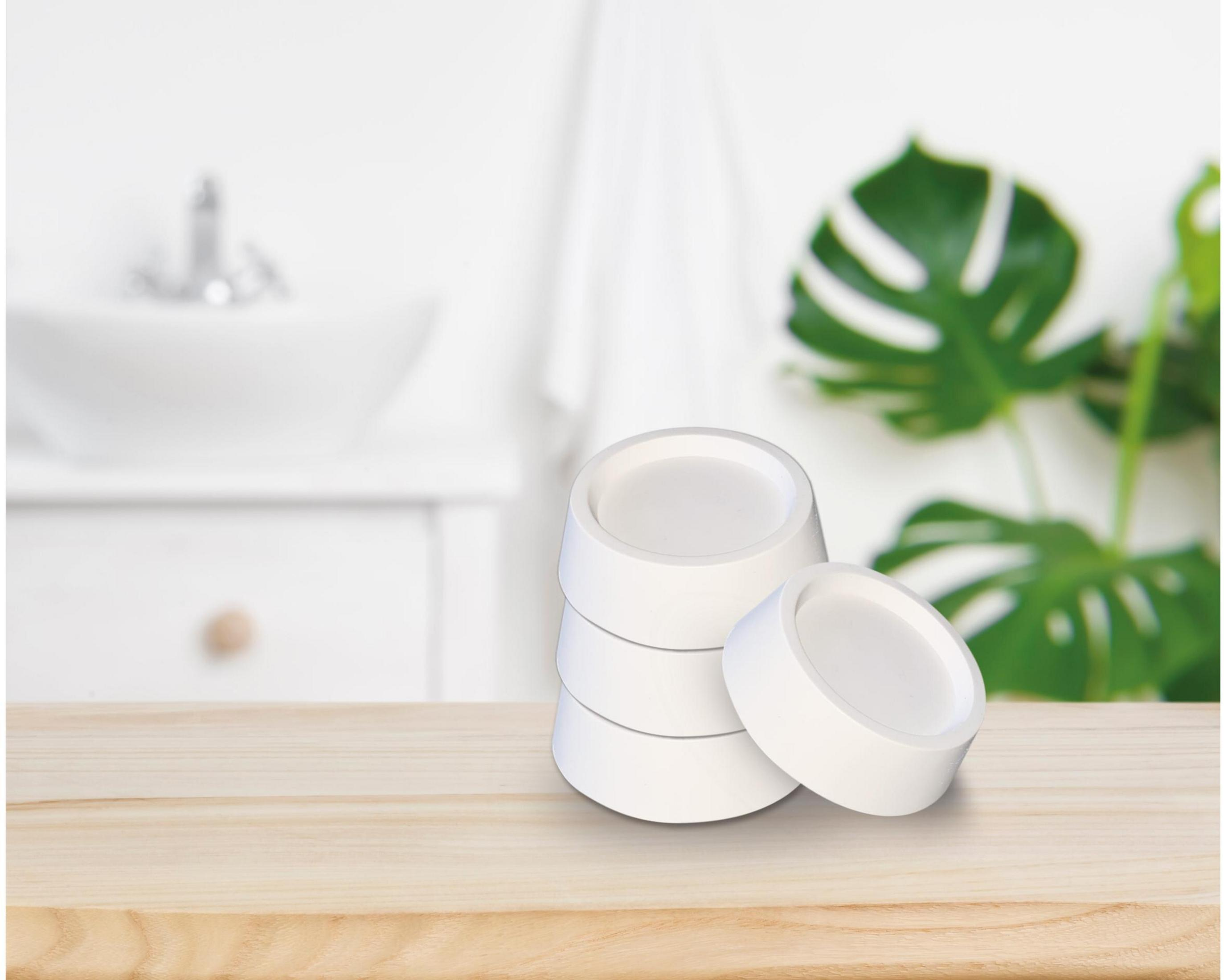Copas blancas sobre una mesa de madera frente a un baño.