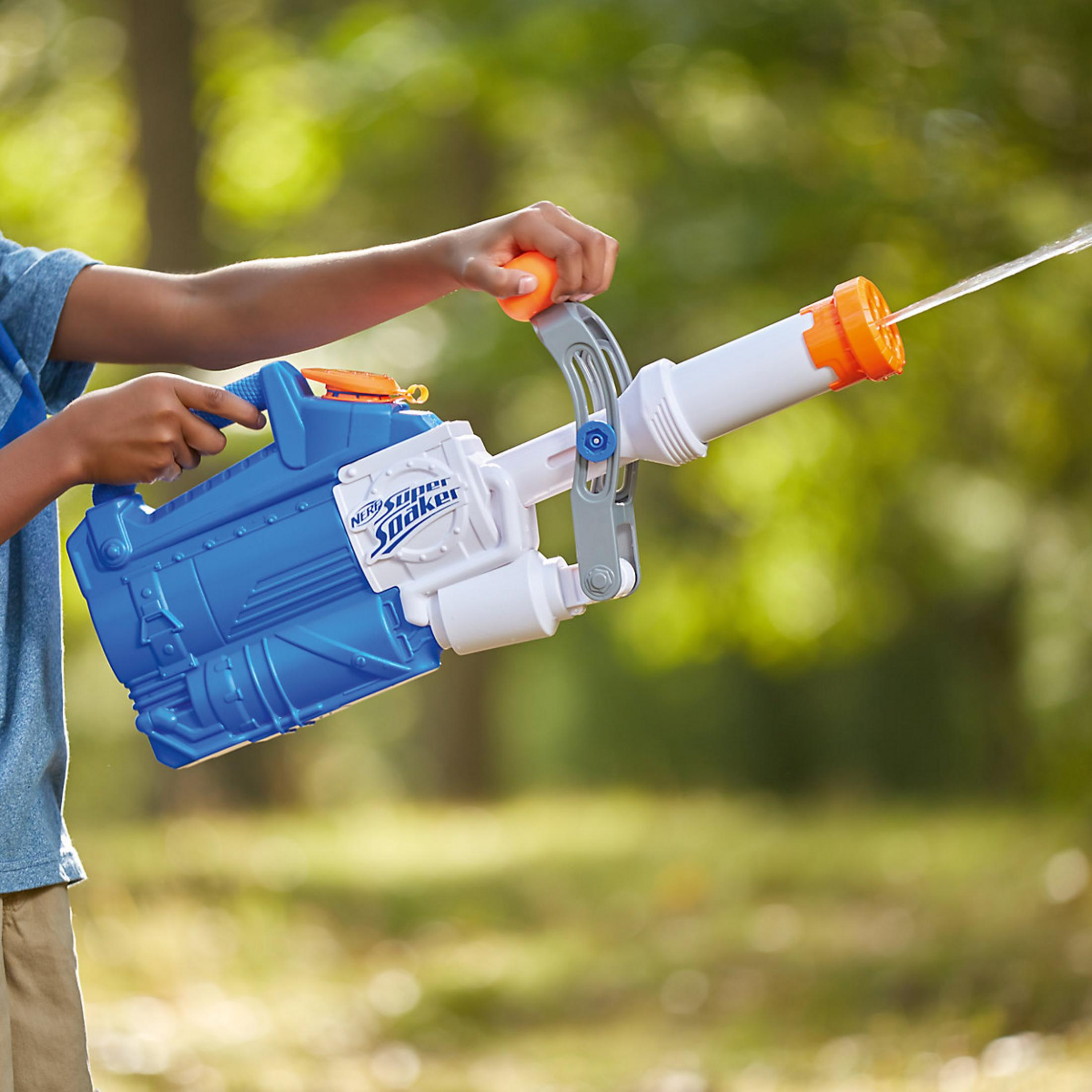Bambino tiene Nerf Super Soaker blu, spara acqua all'aperto.