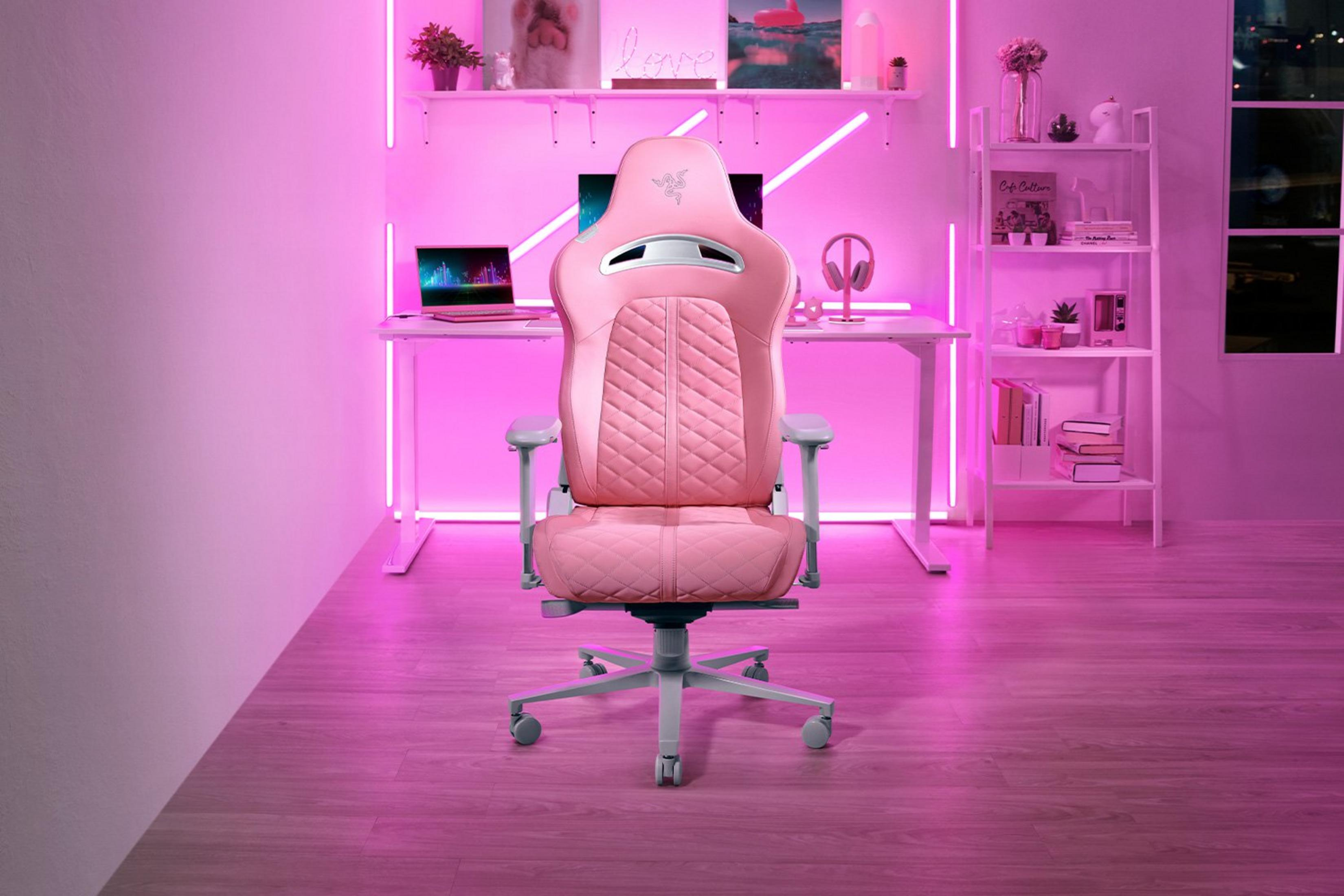 Ein rosafarbener Gaming-Stuhl steht vor einem Schreibtisch mit Laptop. Neonlicht beleuchtet den Raum.
