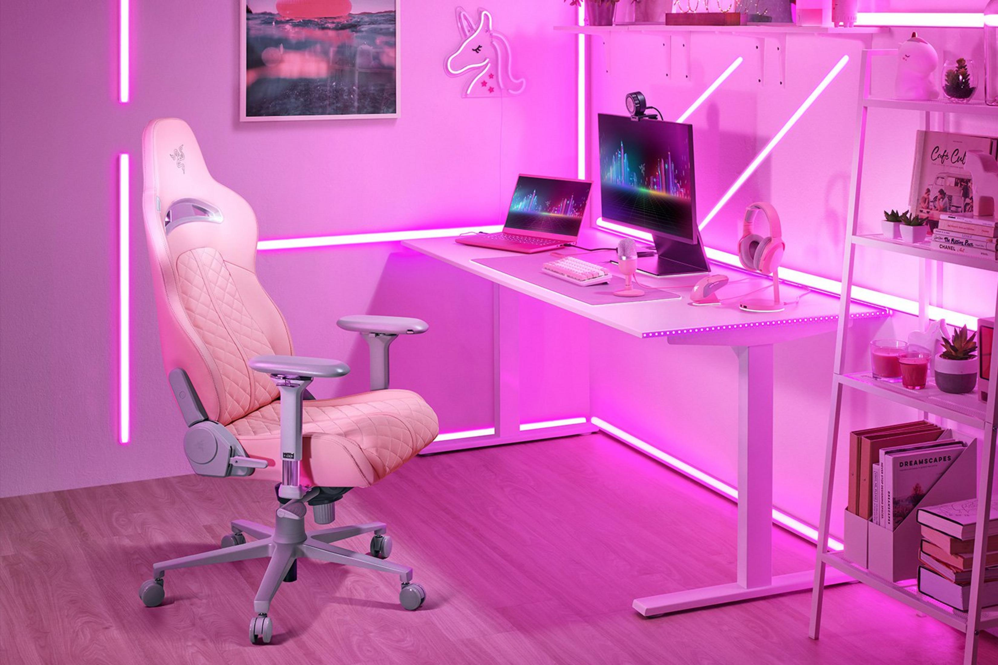Ein rosafarbener Gaming-Stuhl steht neben einem Schreibtisch mit Computerausrüstung.