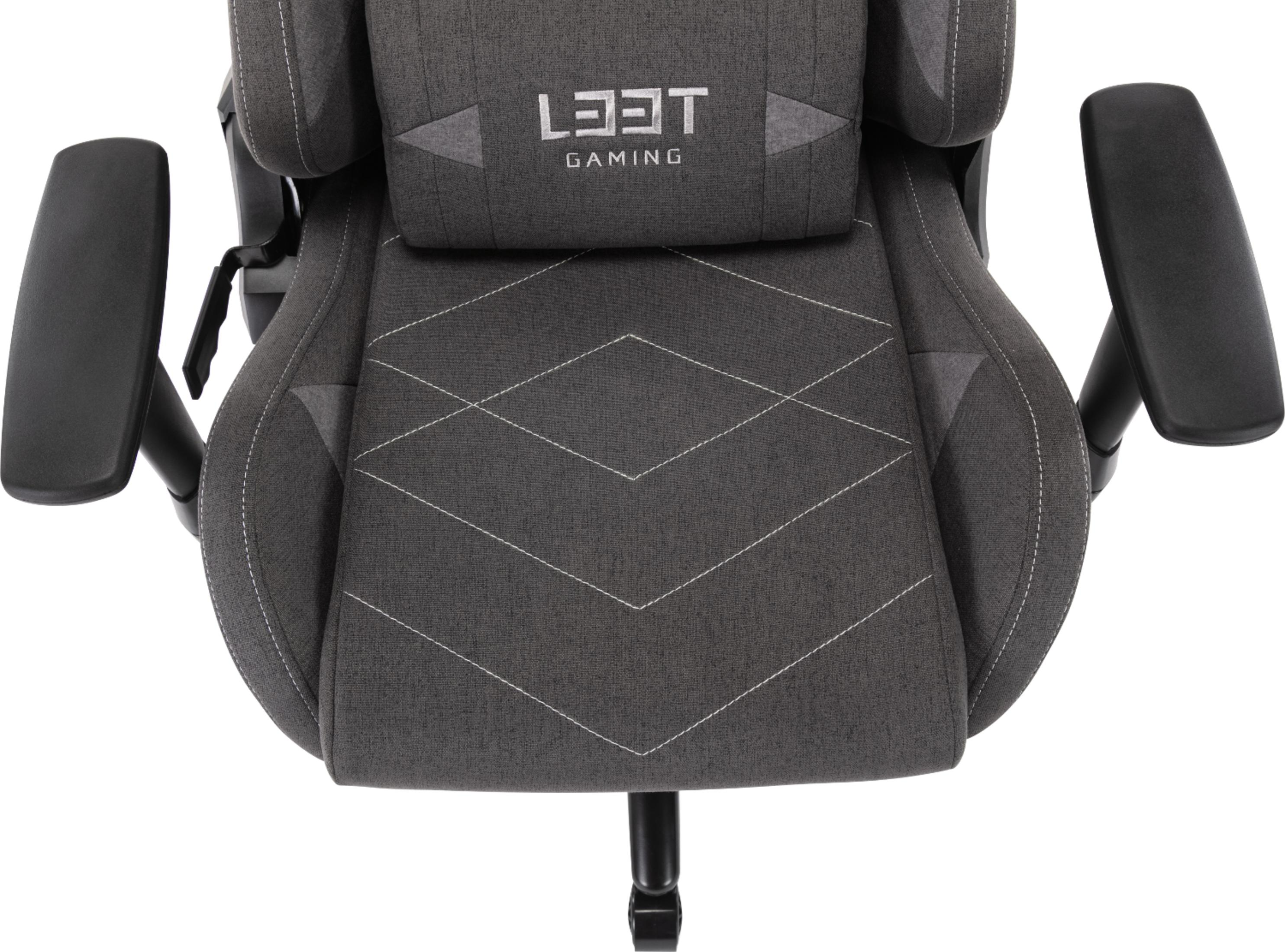 Grauer Gaming-Stuhl mit schwarzem Logo und weißen Nähten. Armlehnen sind sichtbar.