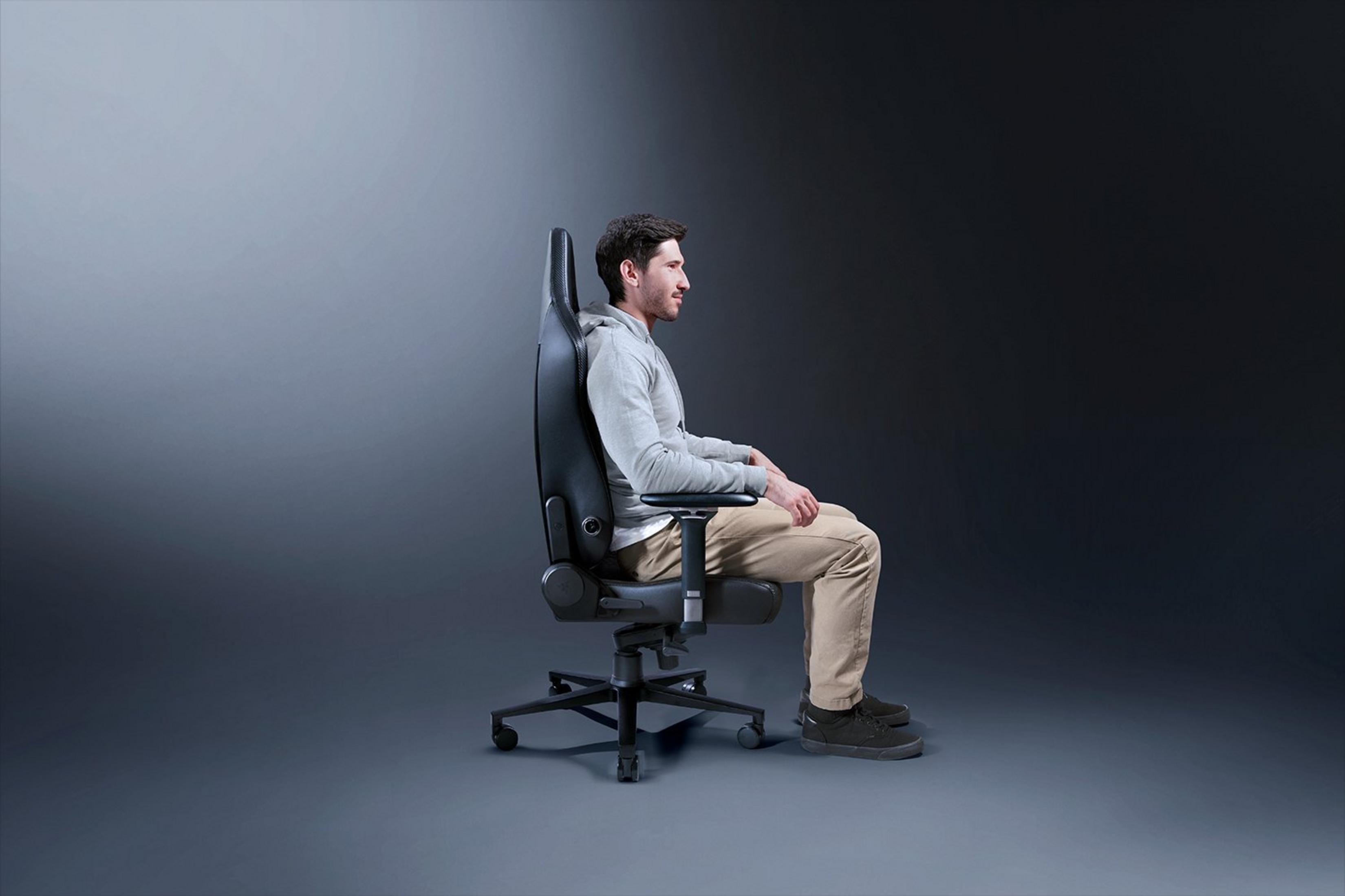 Ein Mann sitzt in einem schwarzen Gaming-Stuhl. Der Stuhl hat ein hohes Rückenteil.