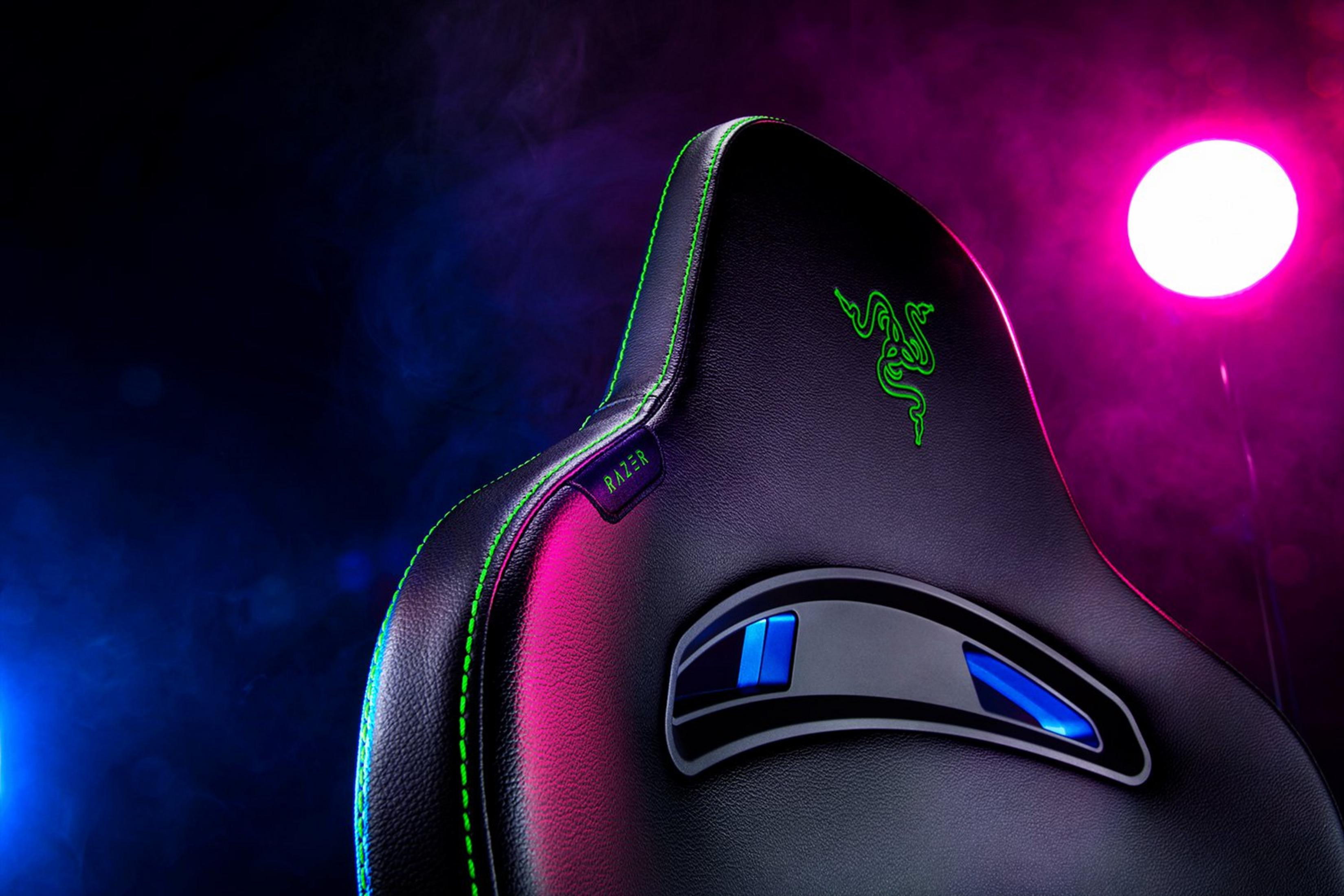Yeşil dikişli ve logolu siyah Razer oyuncu koltuğu, aydınlatmalı.