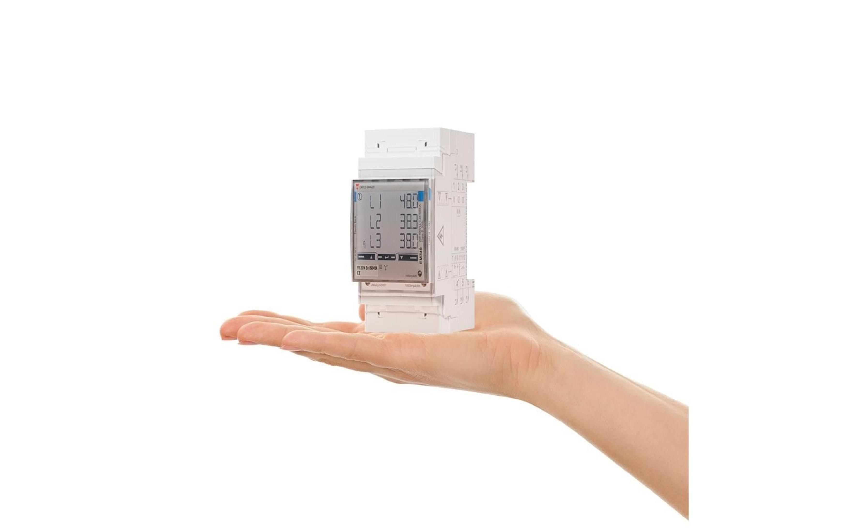 Eine Hand hält ein weißes elektrisches Messgerät mit digitaler Anzeige.