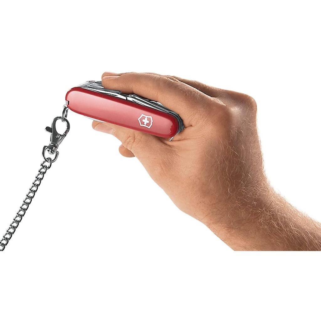 Kırmıızı bir İsviçre çakısı zincirle bir elde tutuluyor.