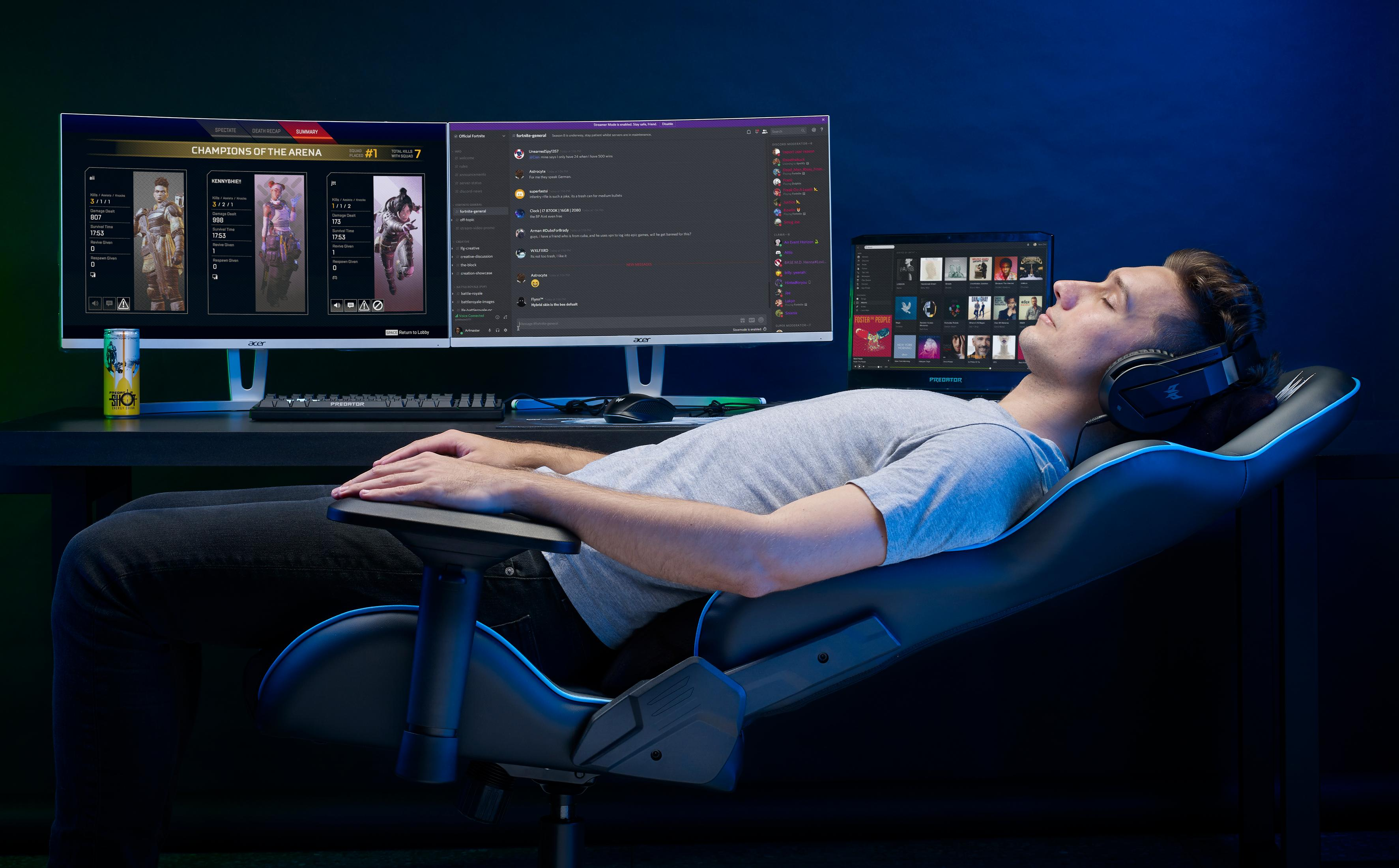 Un uomo con cuffie riposa su una sedia da gaming davanti a tre monitor.