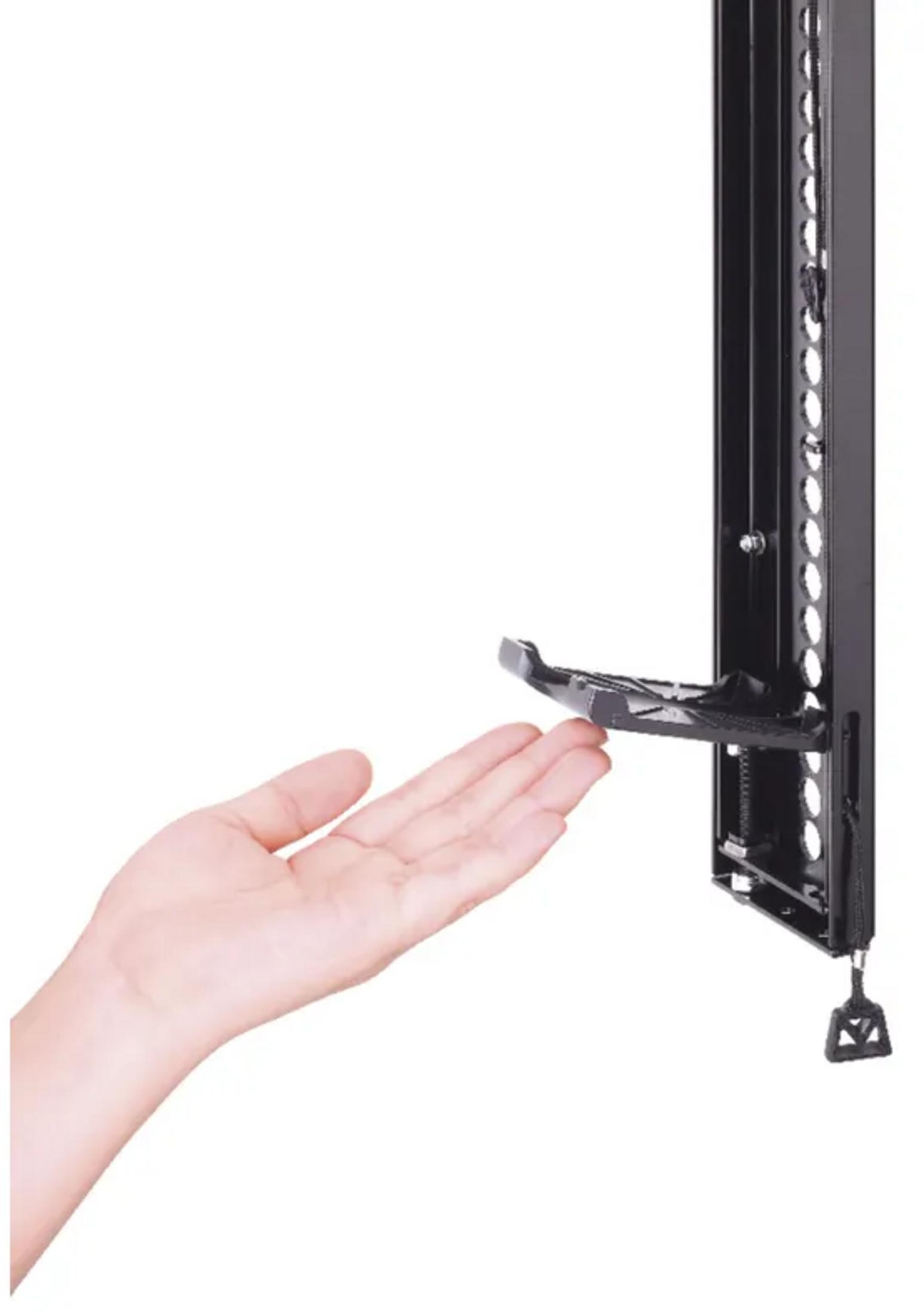 A hand reaches towards a black metal rack with a small shelf.