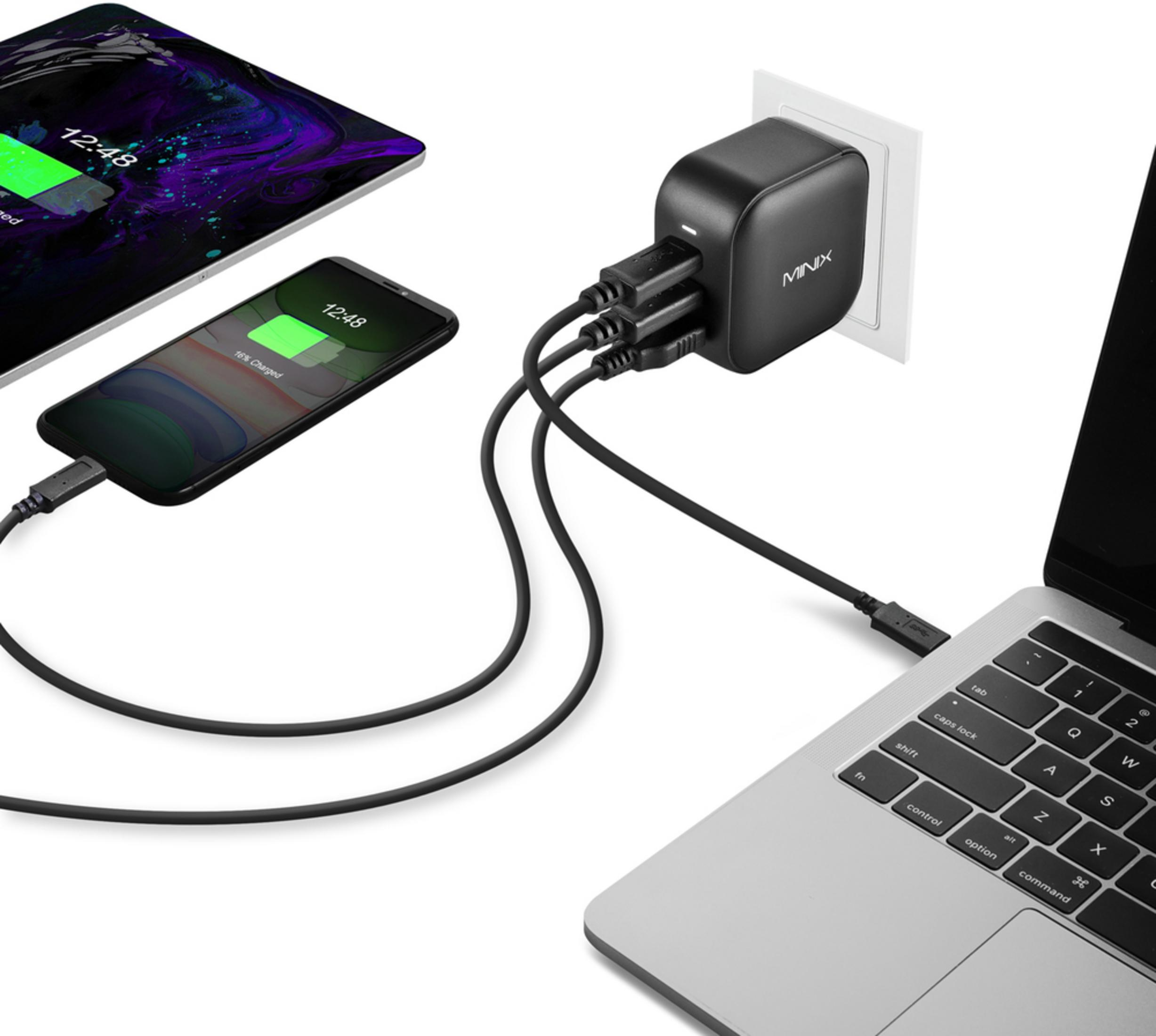 Un alimentatore nero carica uno smartphone, un tablet e un laptop.