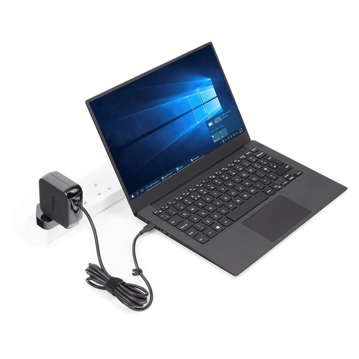 A black laptop is plugged into a white power strip via a black charger.
