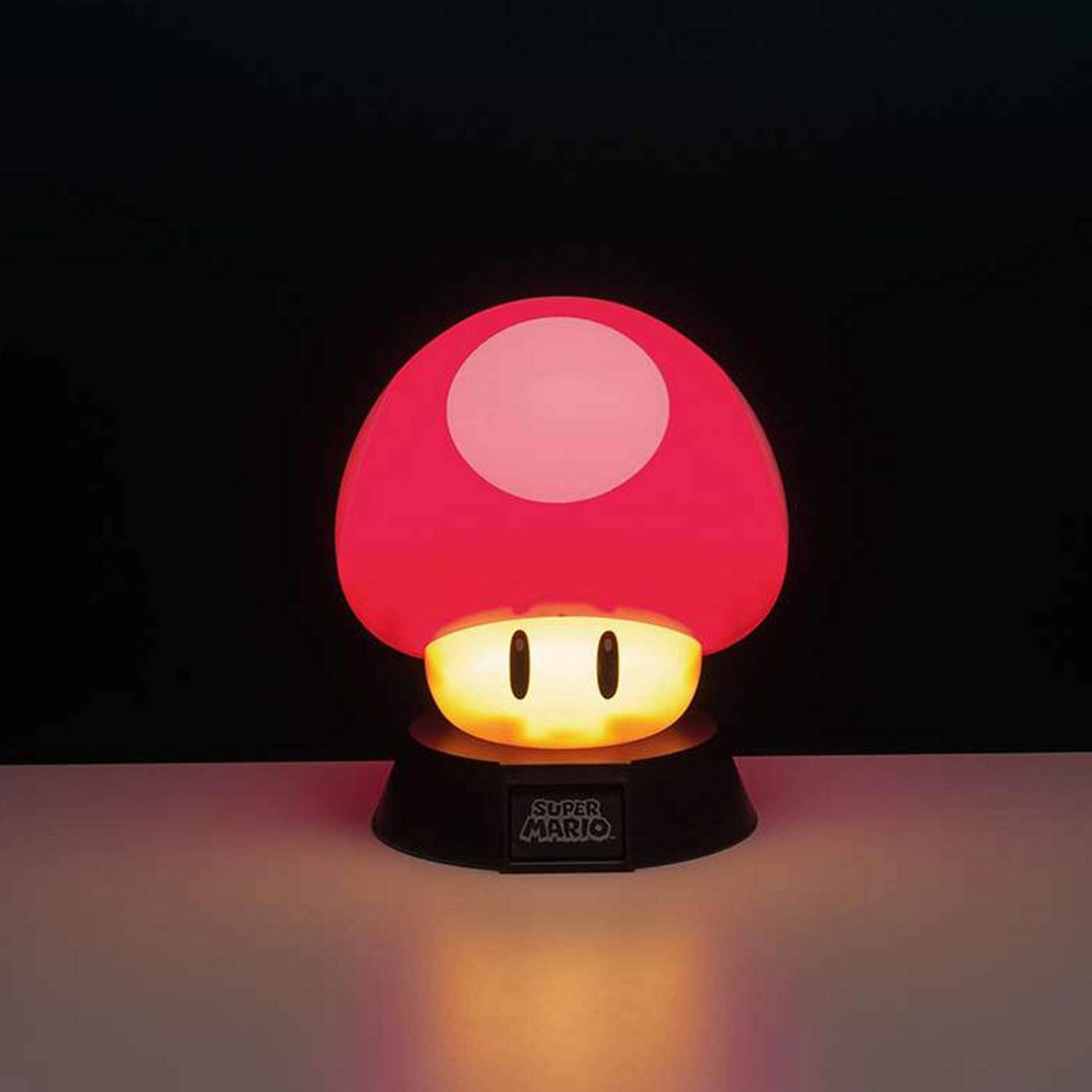 Czerwona lampa w kształcie grzyba z logo Super Mario świeci na stole.