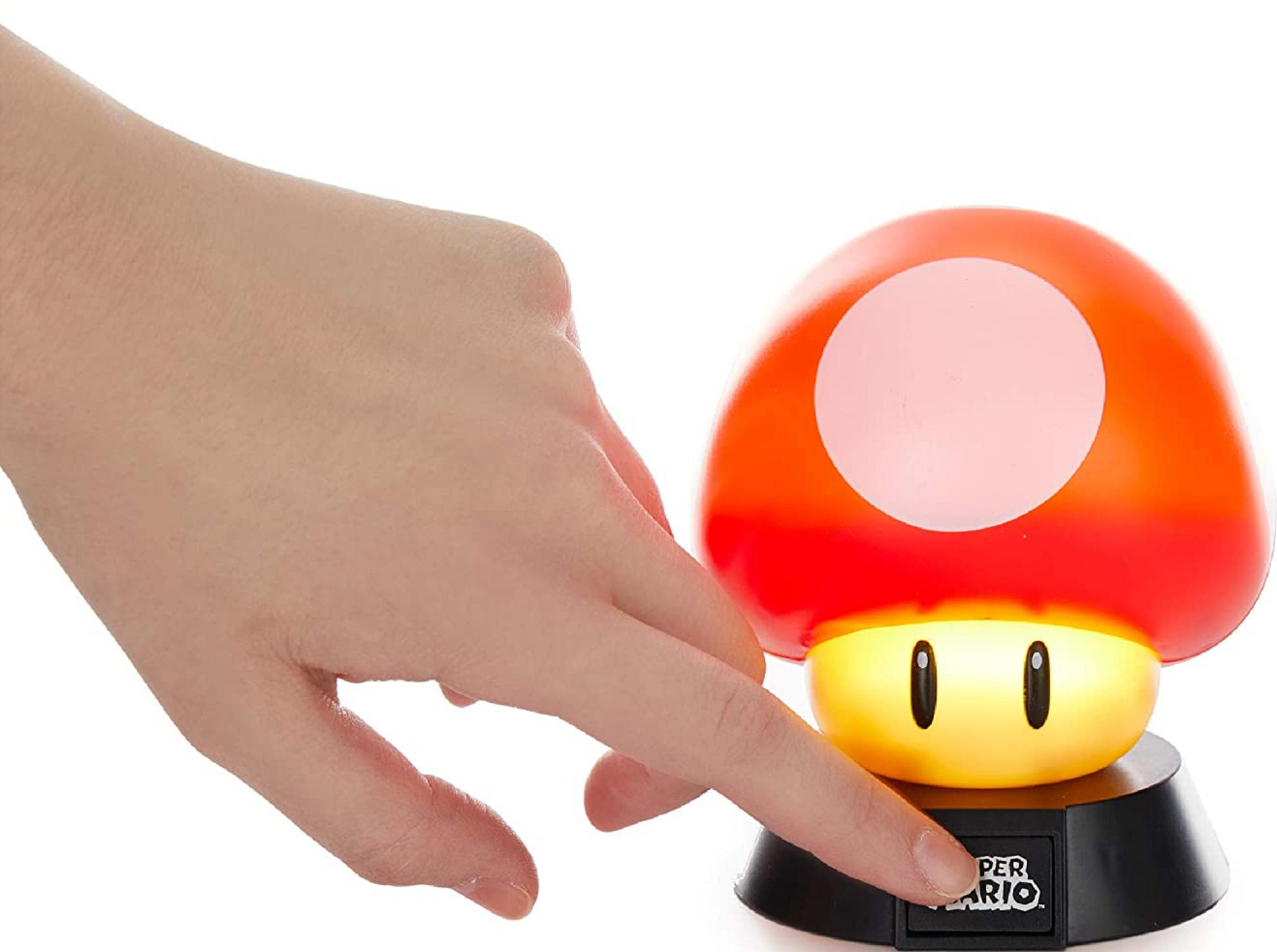 Palec naciska przycisk grzyba Mario.