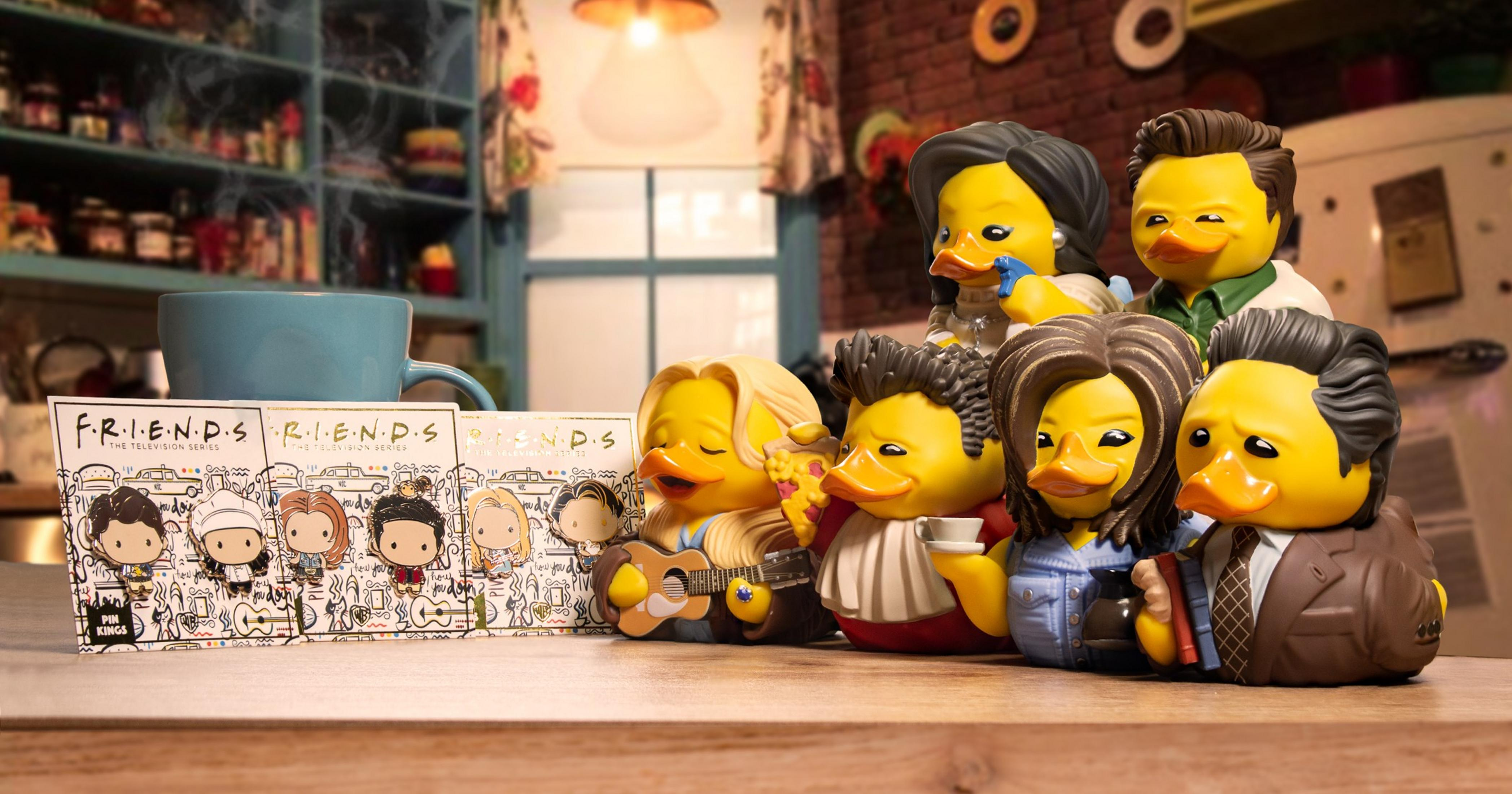 Friends-Entenfiguren mit Gitarre, Pizza, Kaffee und Büchern vor dem TV-Serien-Logo.