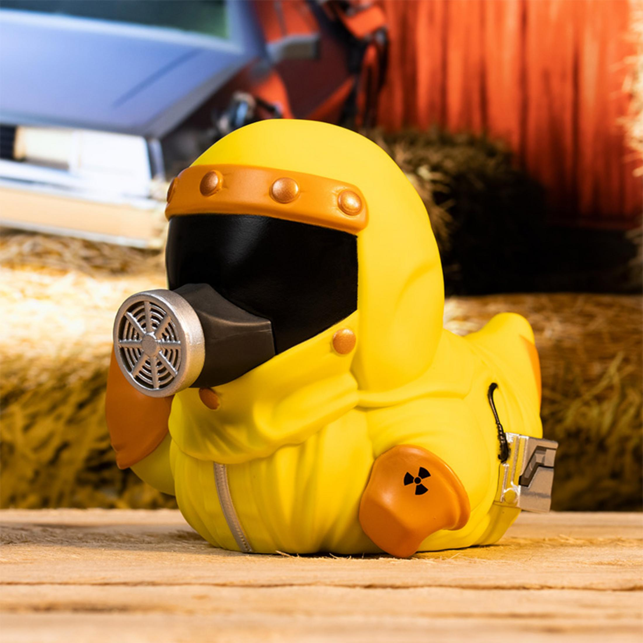 Gelbe Ente in Schutzanzug mit Gasmaske und Atomsymbol auf Holzboden.