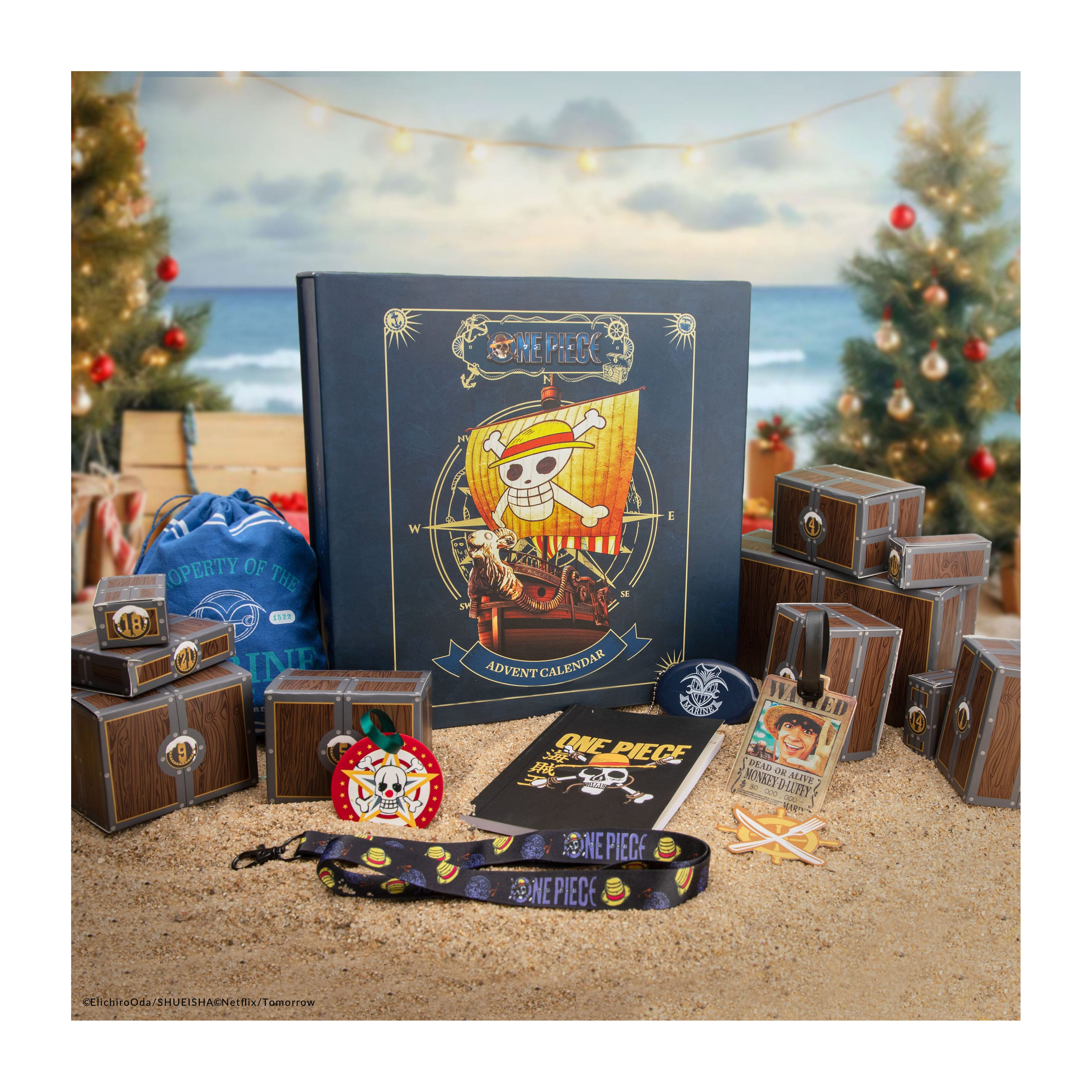 Ein One Piece Adventskalender mit Schatztruhen auf Sand, vor Weihnachtsbäumen.