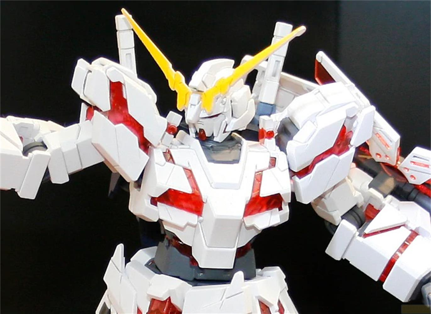 Weißes Gundam-Modell mit roten Akzenten und gelbem Horn. Schwarzer Hintergrund.
