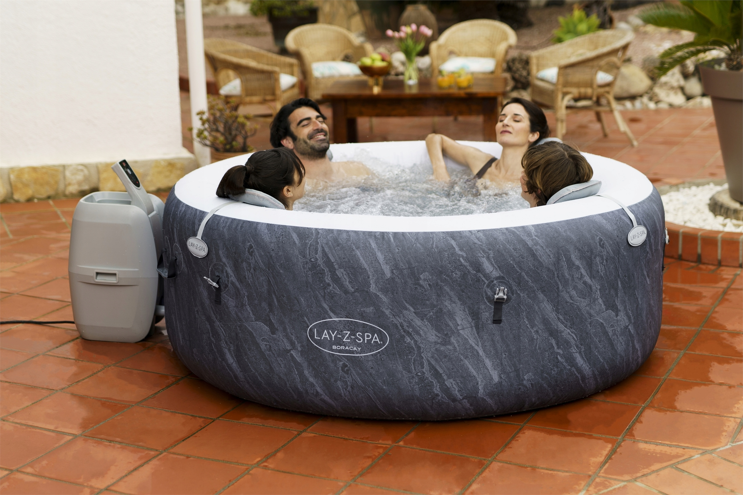 Cztery osoby relaksują się w nadmuchiwanym jacuzzi na zewnątrz.
