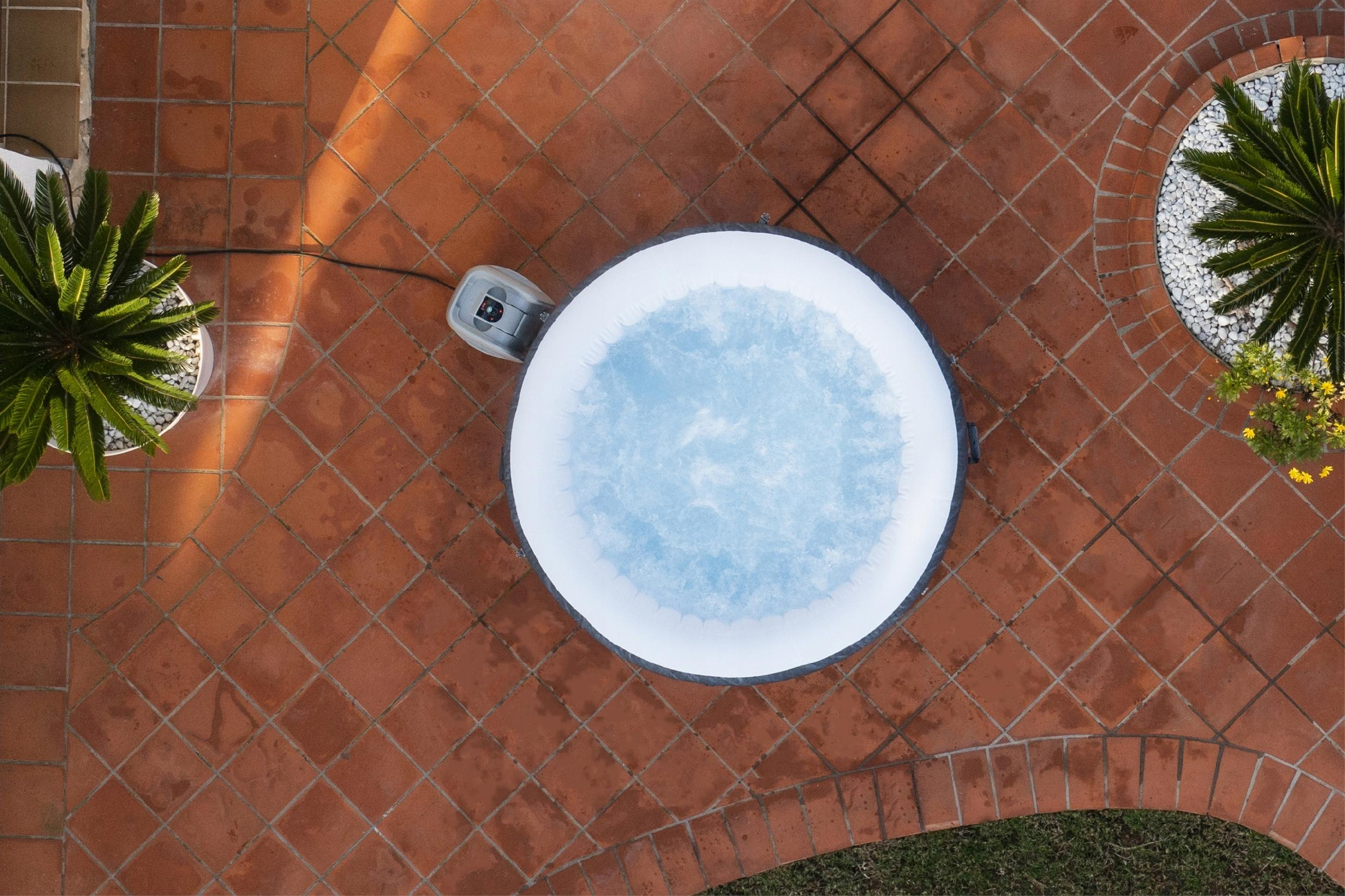 Nadmuchiwany jacuzzi z niebieską wodą stoi na powierzchni wyłożonej terakotową terakotą.
