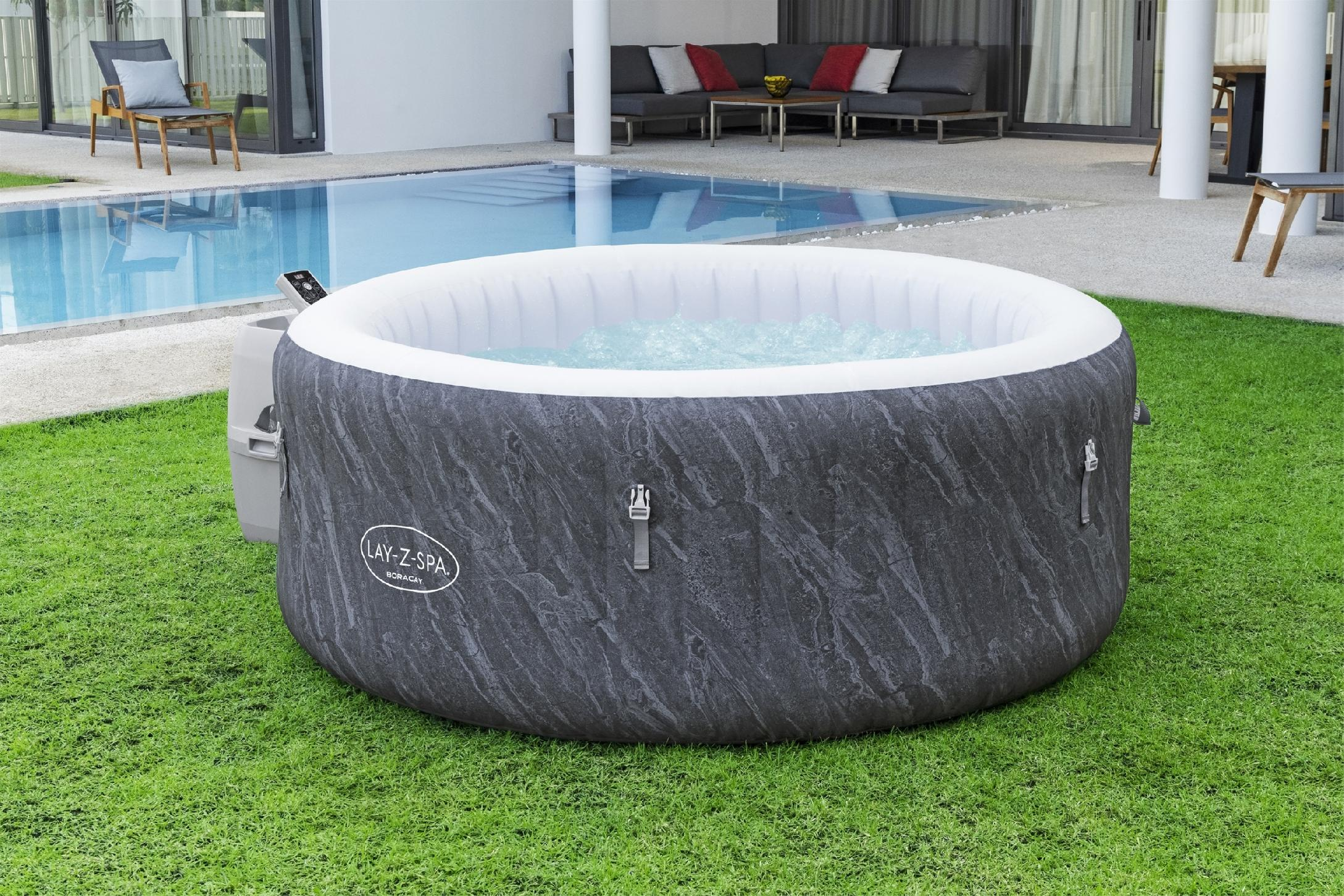 Nadmuchiwany jacuzzi z szarym wzorem marmuru na zielonej trawie obok basenu.