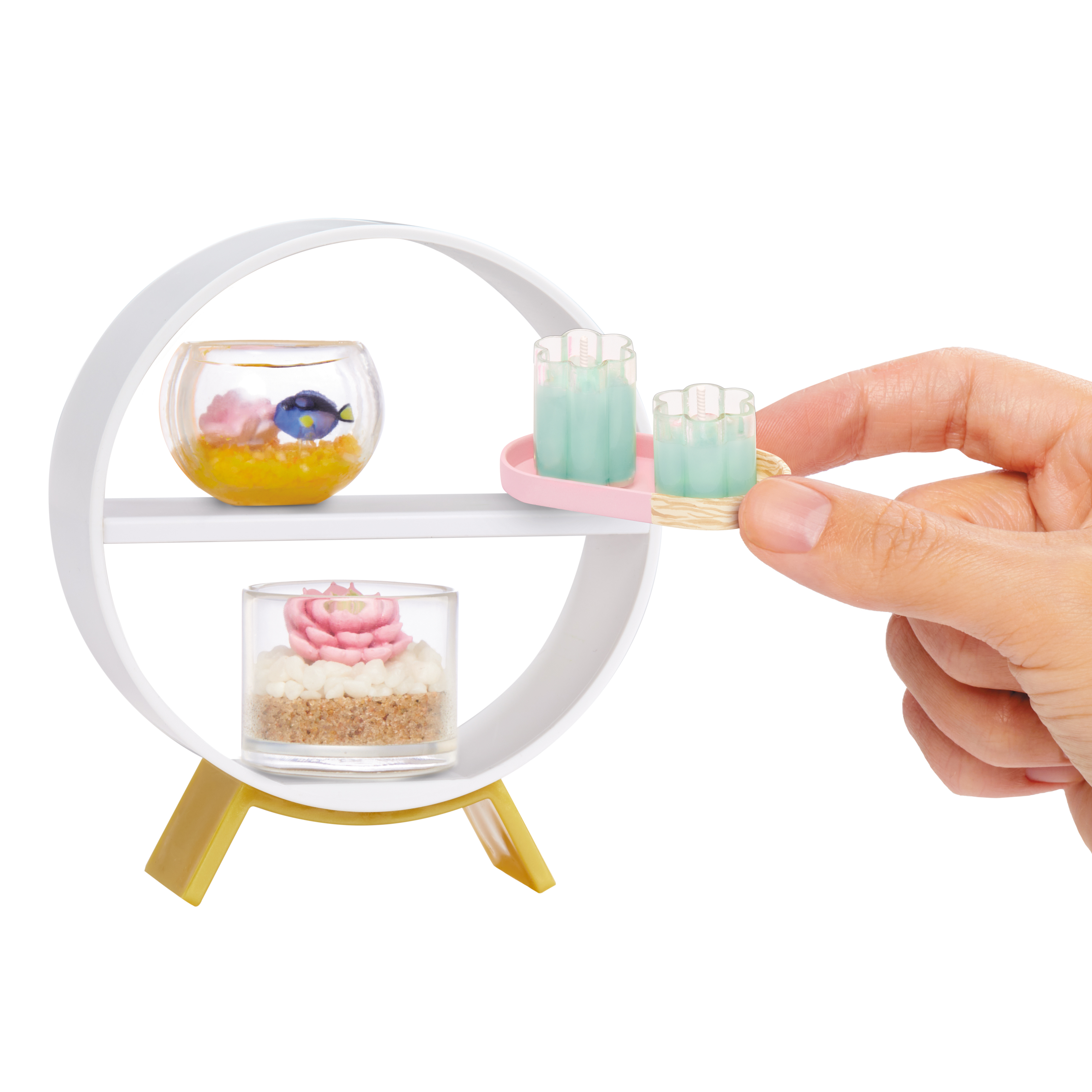 Ein runder weißer Ständer mit Miniatur-Dekorationen: Fischglas, Kuchen und Kerzen.