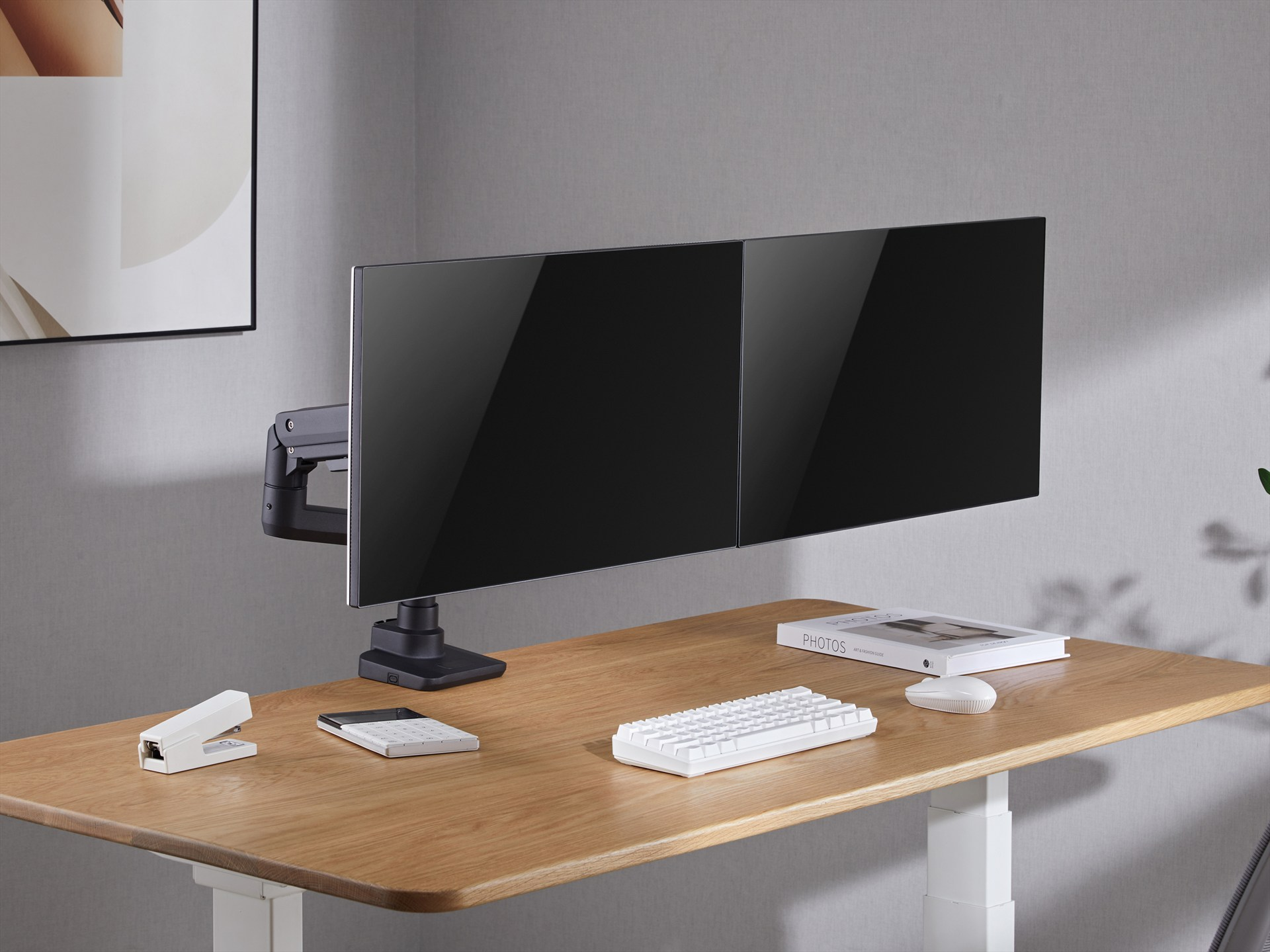 Zwei Monitore auf einem Holztisch mit weißer Tastatur, Maus, Rechner und Tacker.
