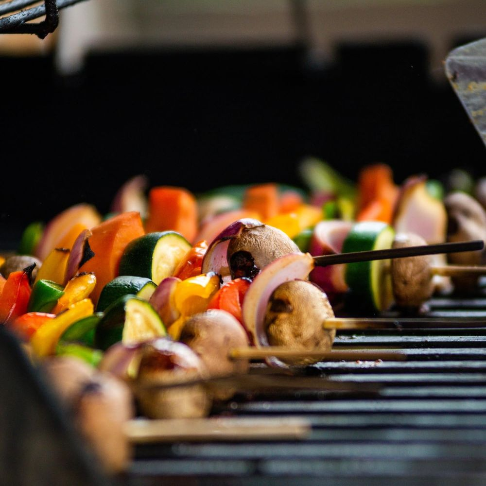 Spiedini di verdure colorate alla griglia su un barbecue con funghi, peperoni, zucchine e cipolle.